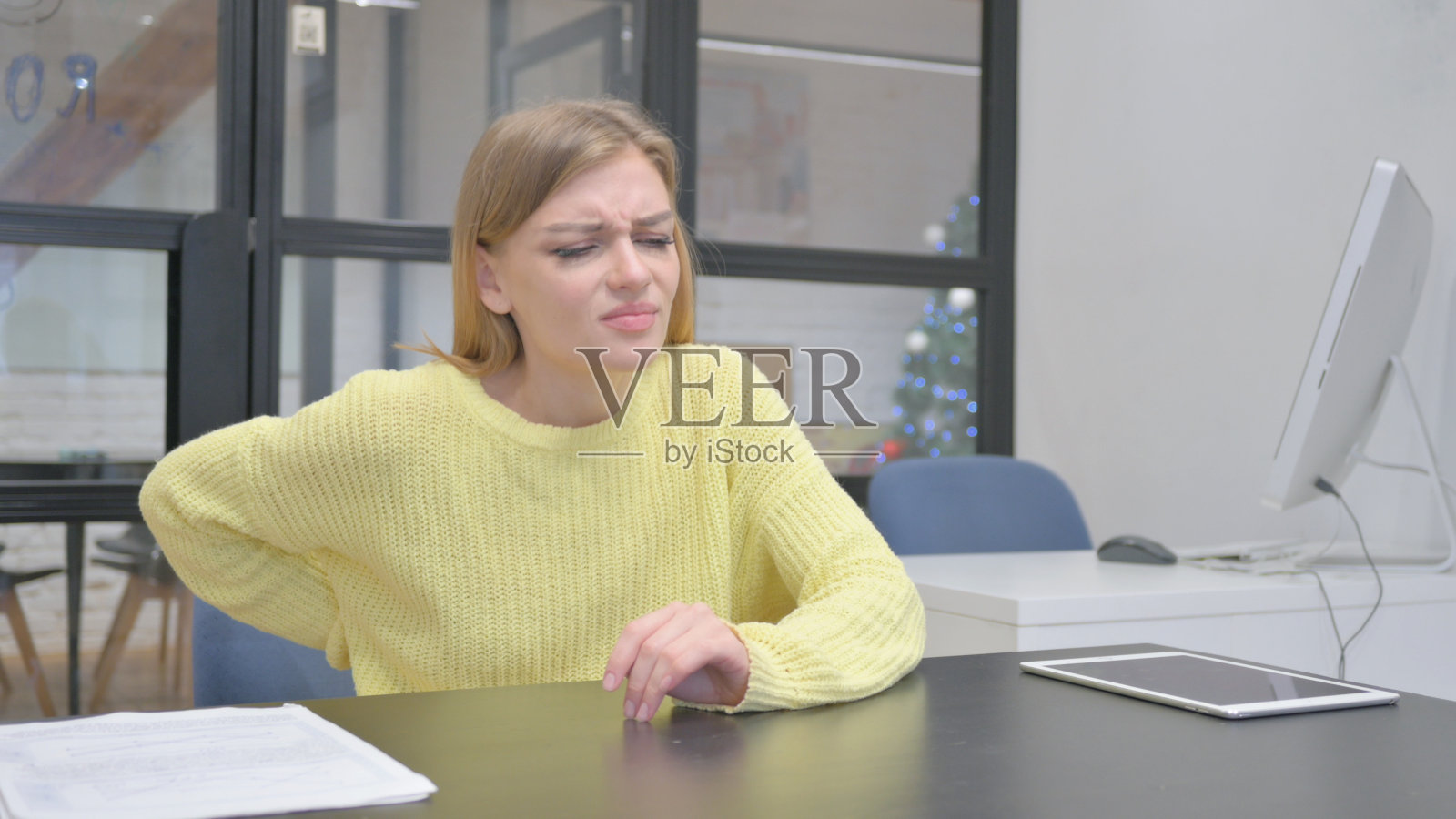 年轻的金发女子试图站起来时背部疼痛照片摄影图片