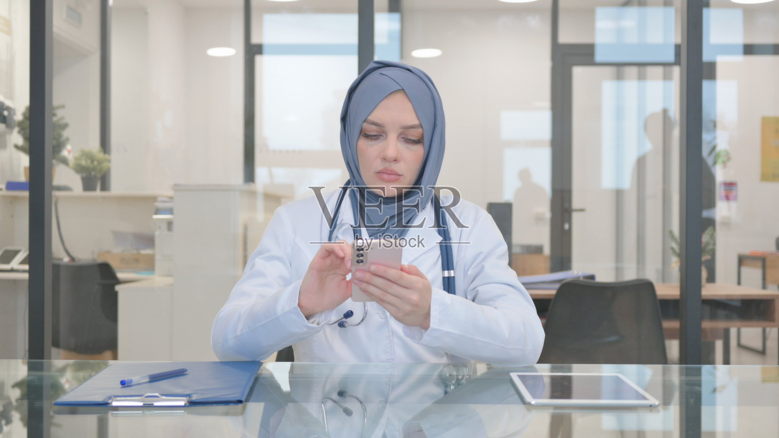 戴头巾的医生在诊所使用电话照片摄影图片