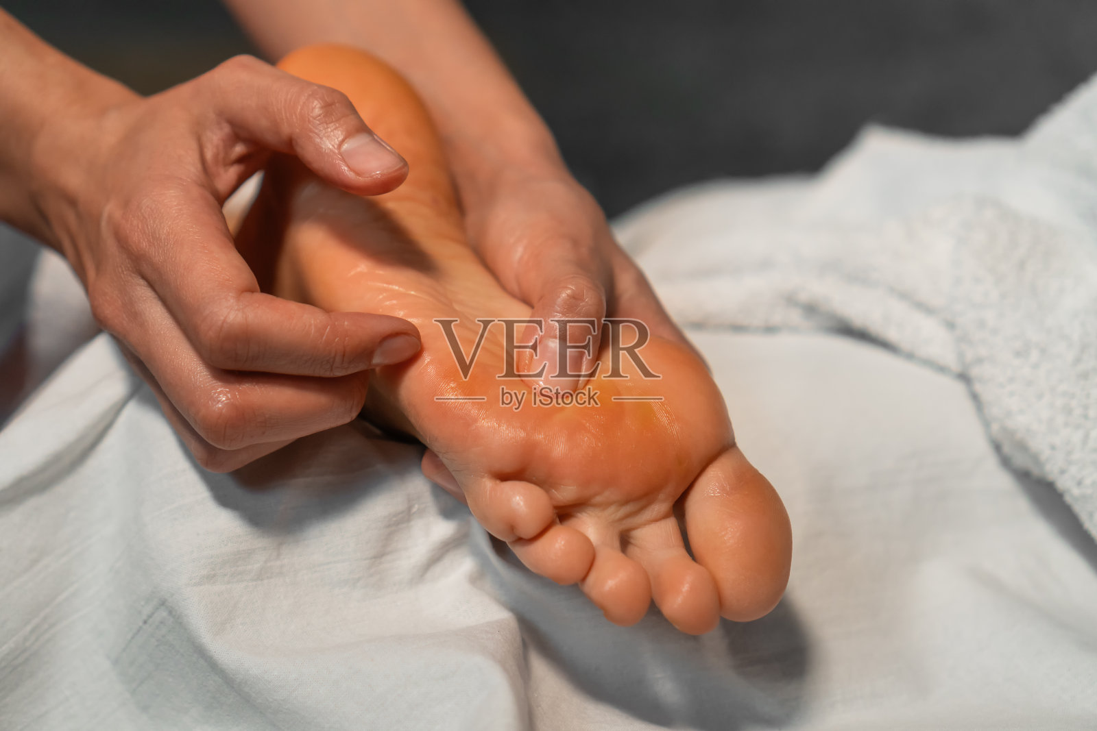 按摩师的手正在给一个年轻女子做足部按摩的特写。专业足底按摩特写。照片摄影图片