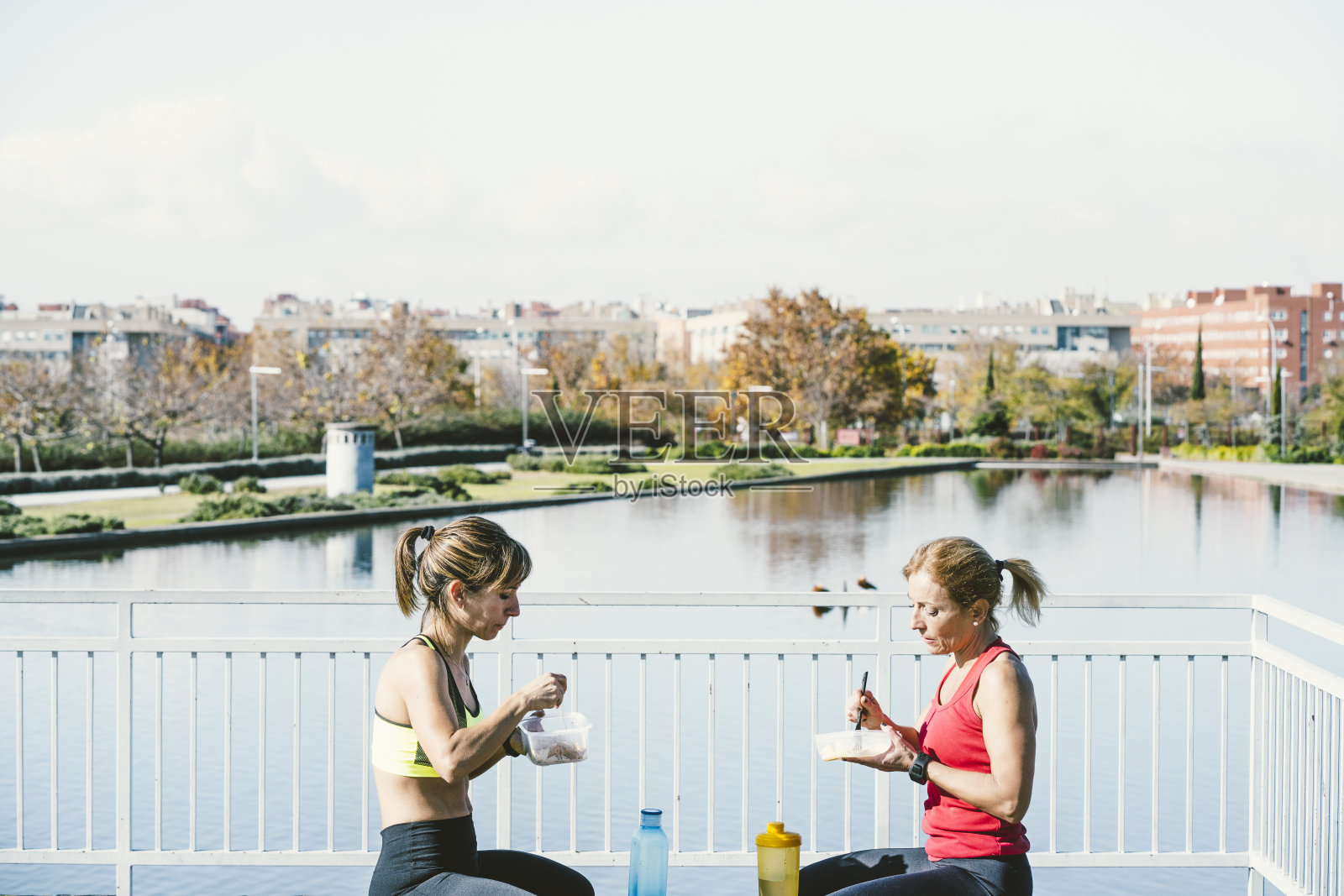 两个女人训练后在公园里吃饭照片摄影图片
