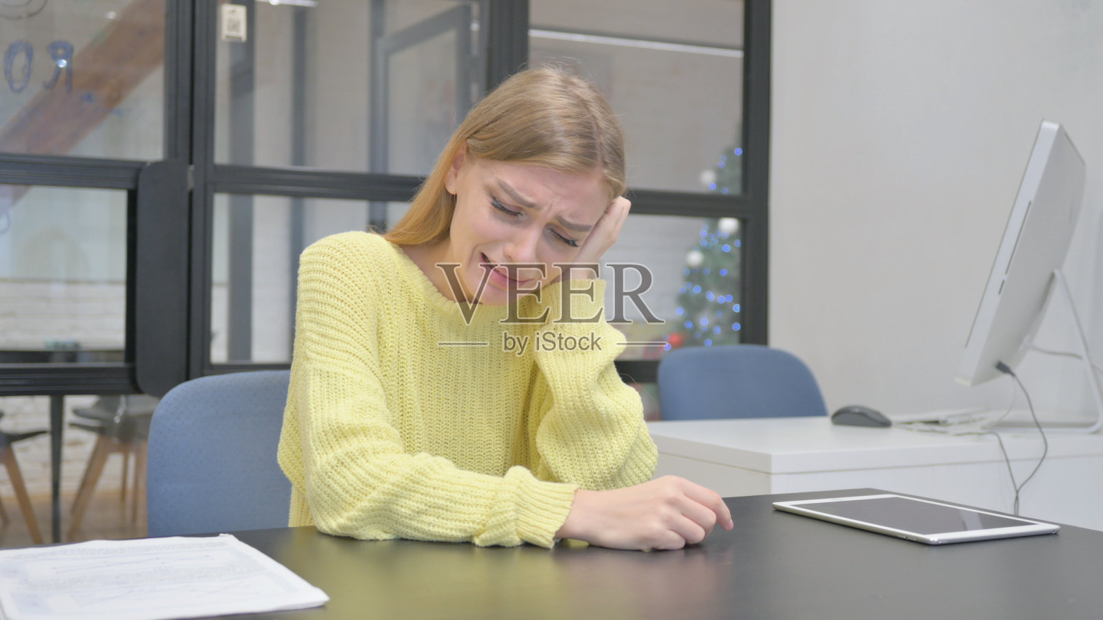 悲伤的年轻金发女人坐在办公室里哭泣照片摄影图片