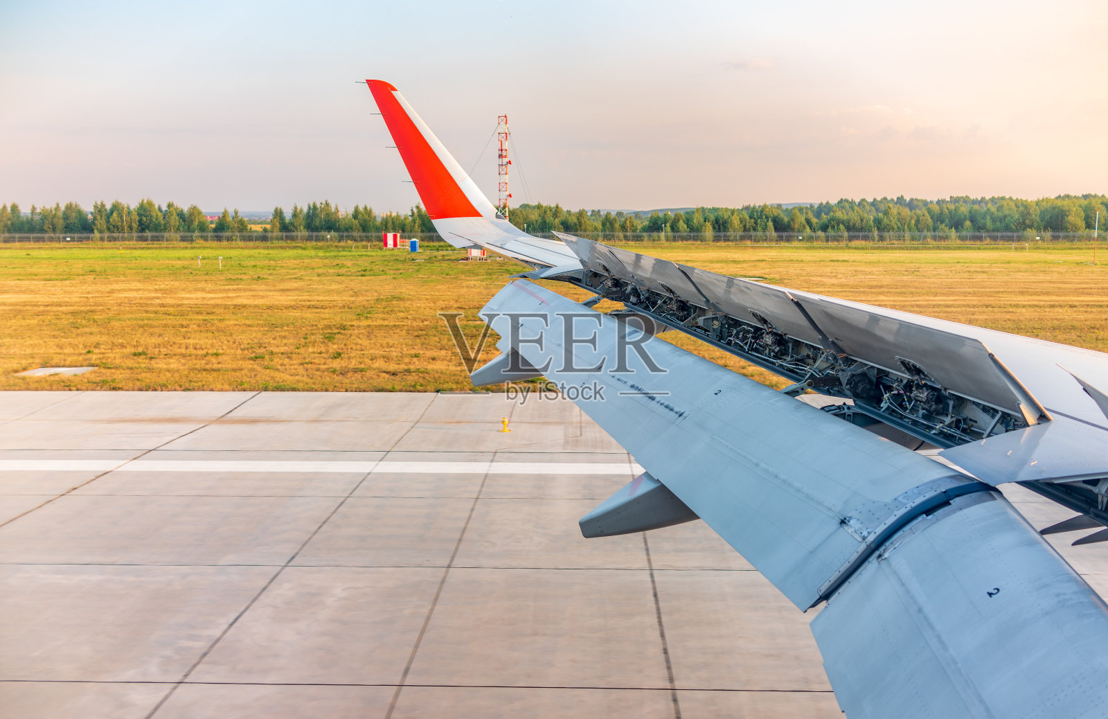飞机机翼的视图，蓝天和绿色的土地在着陆。飞机窗口视图。照片摄影图片