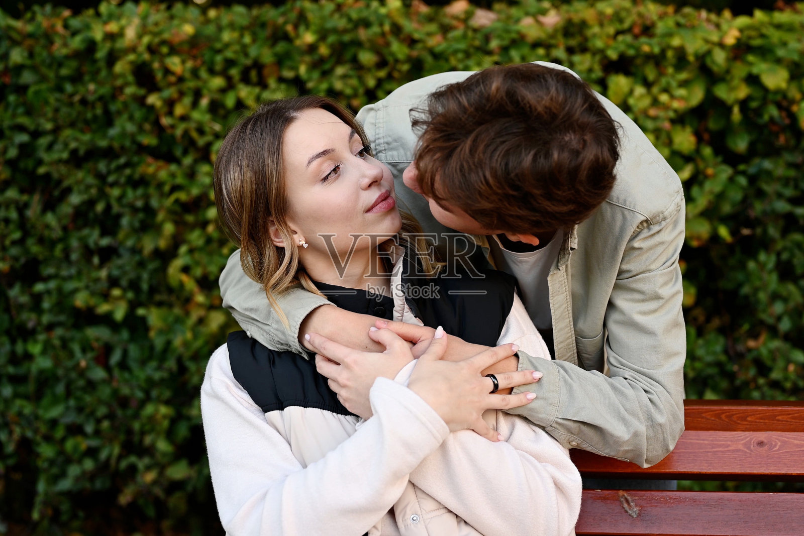 一个男人从后面拥抱坐在长凳上的女朋友照片摄影图片