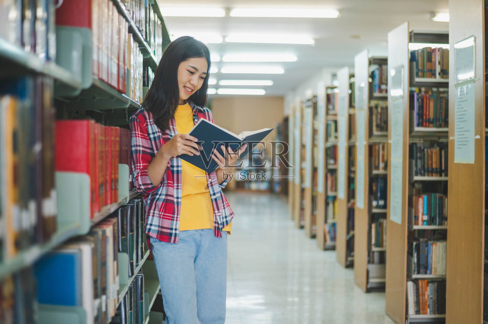 学生们正在阅读和寻找书来学习，做报告，在图书馆的书架上找到有用的信息。读书、学习、智慧的概念。照片摄影图片