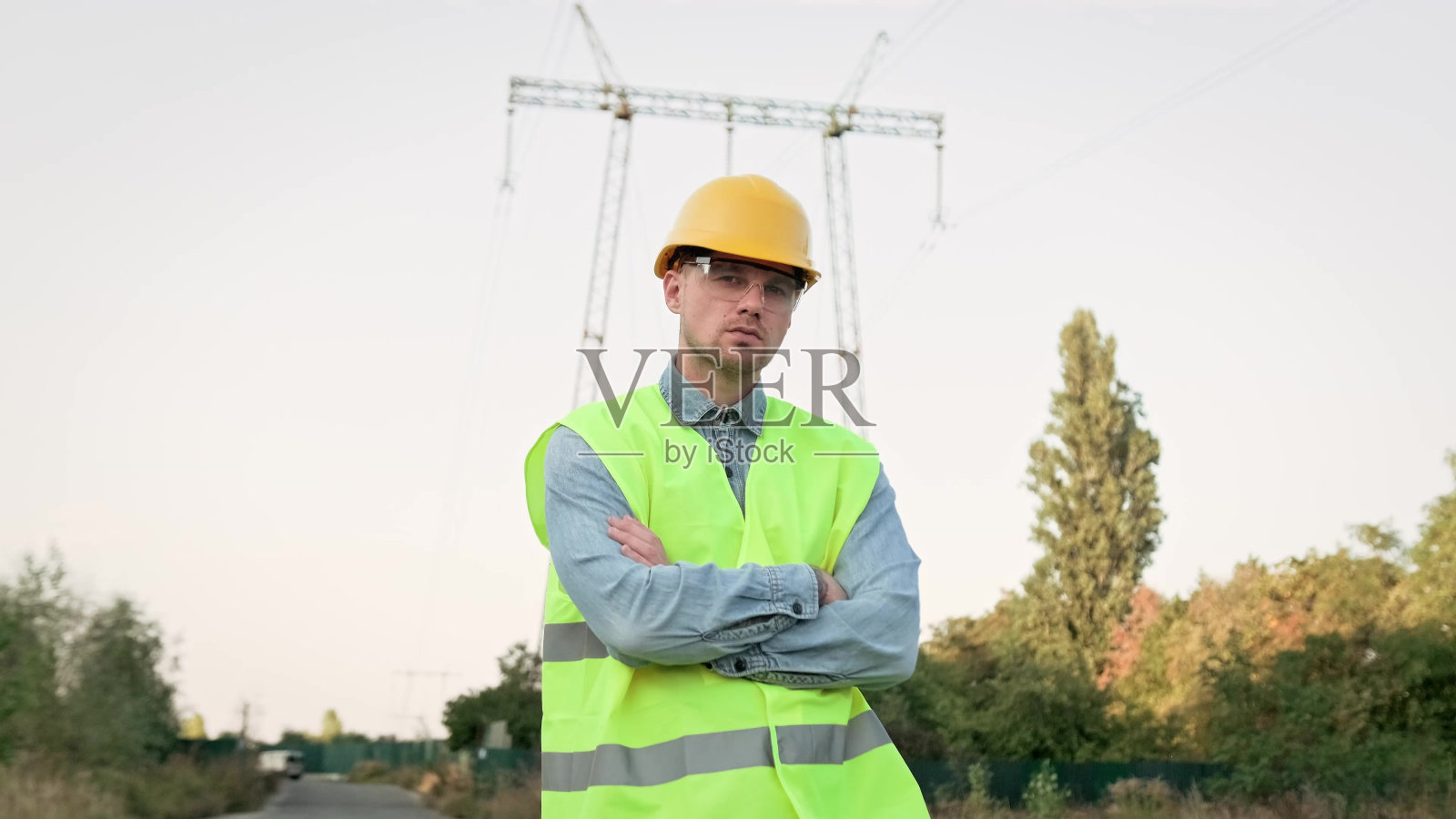 严肃的电力线检查员对着输电塔摆姿势拍照照片摄影图片