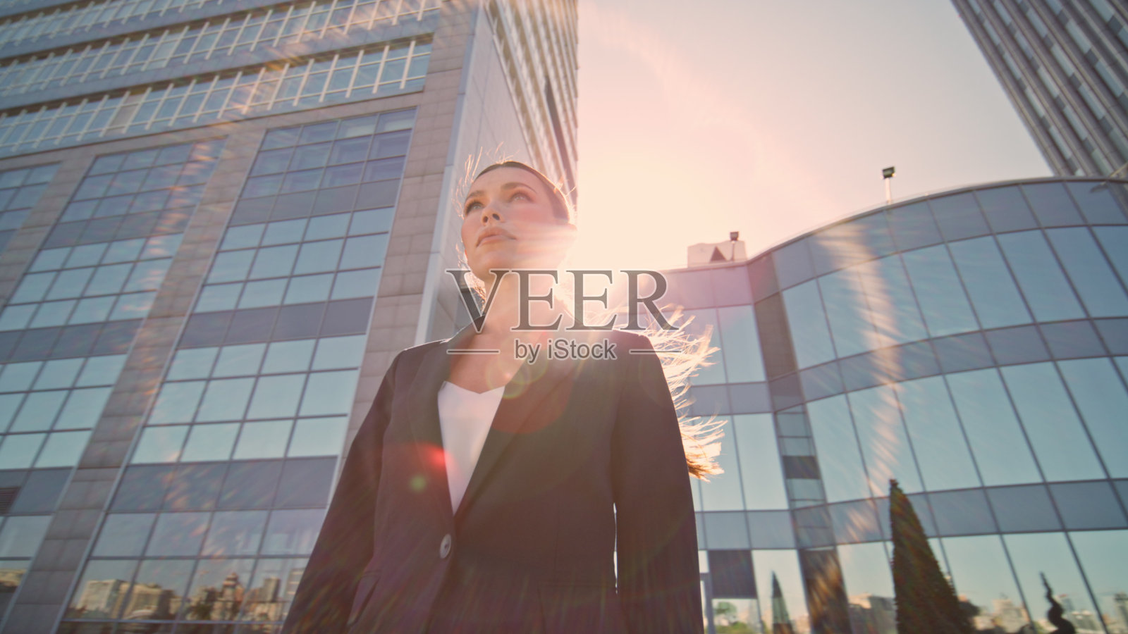 优雅的女商人站在阳光下看着远方。女老板摆姿势照片摄影图片