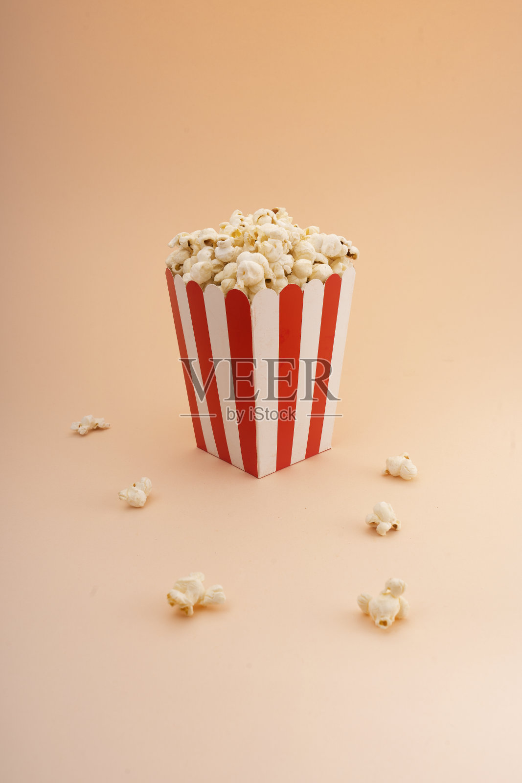 褐色背景上的条纹爆米花桶。照片摄影图片