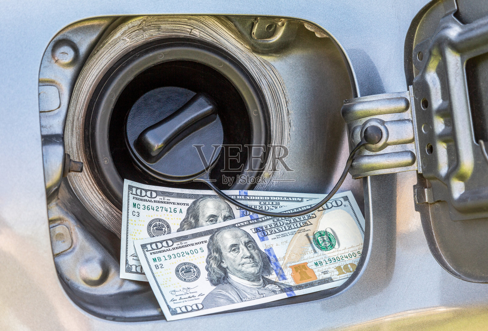 一个打开的油箱上贴着200美元钞票，象征着油价的上涨照片摄影图片