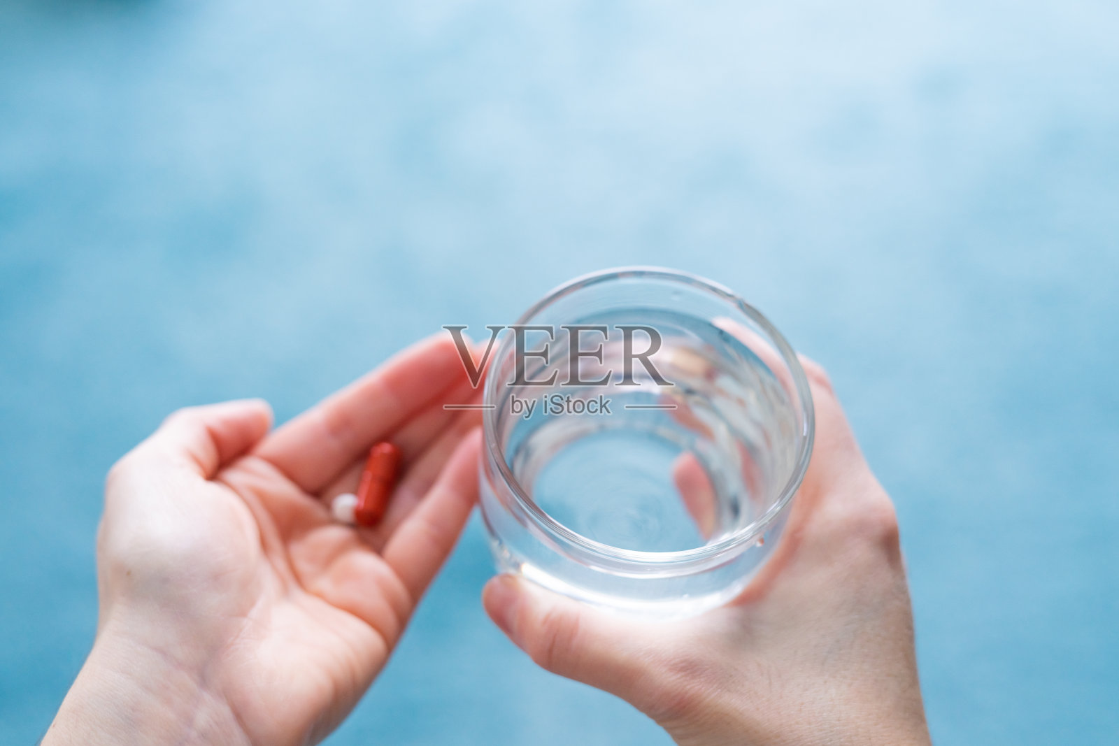 手里拿着药片和一杯水。医药和健康。照片摄影图片