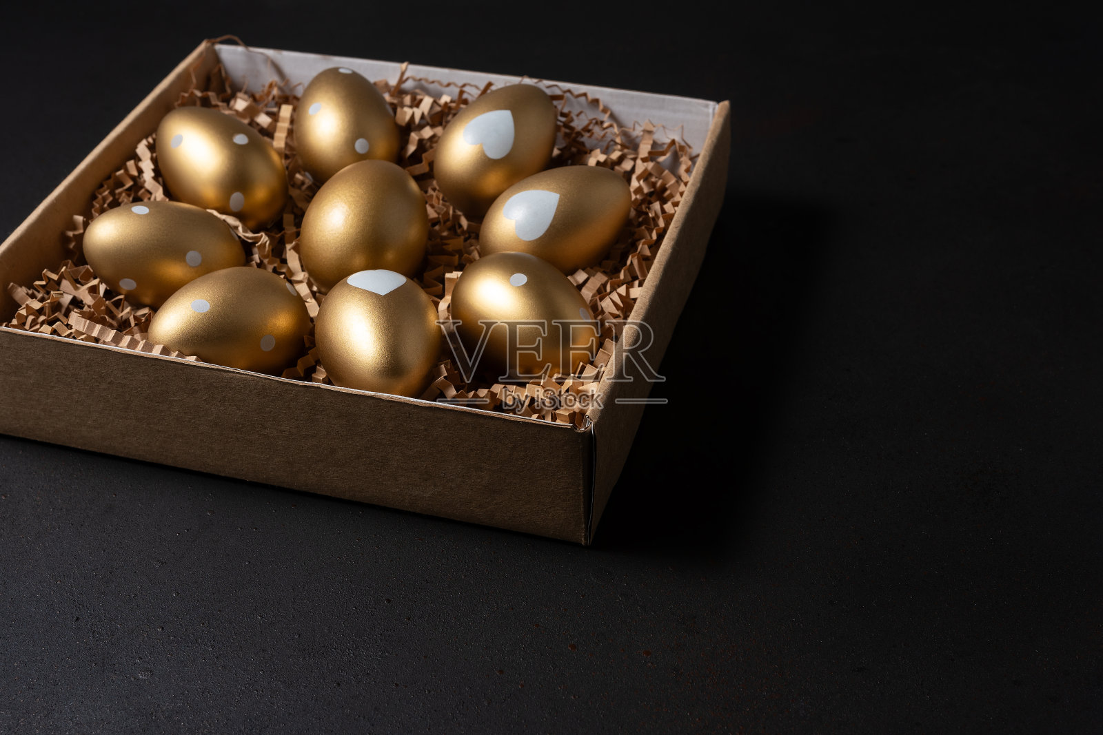黑色背景的纸盒里的金蛋。照片摄影图片