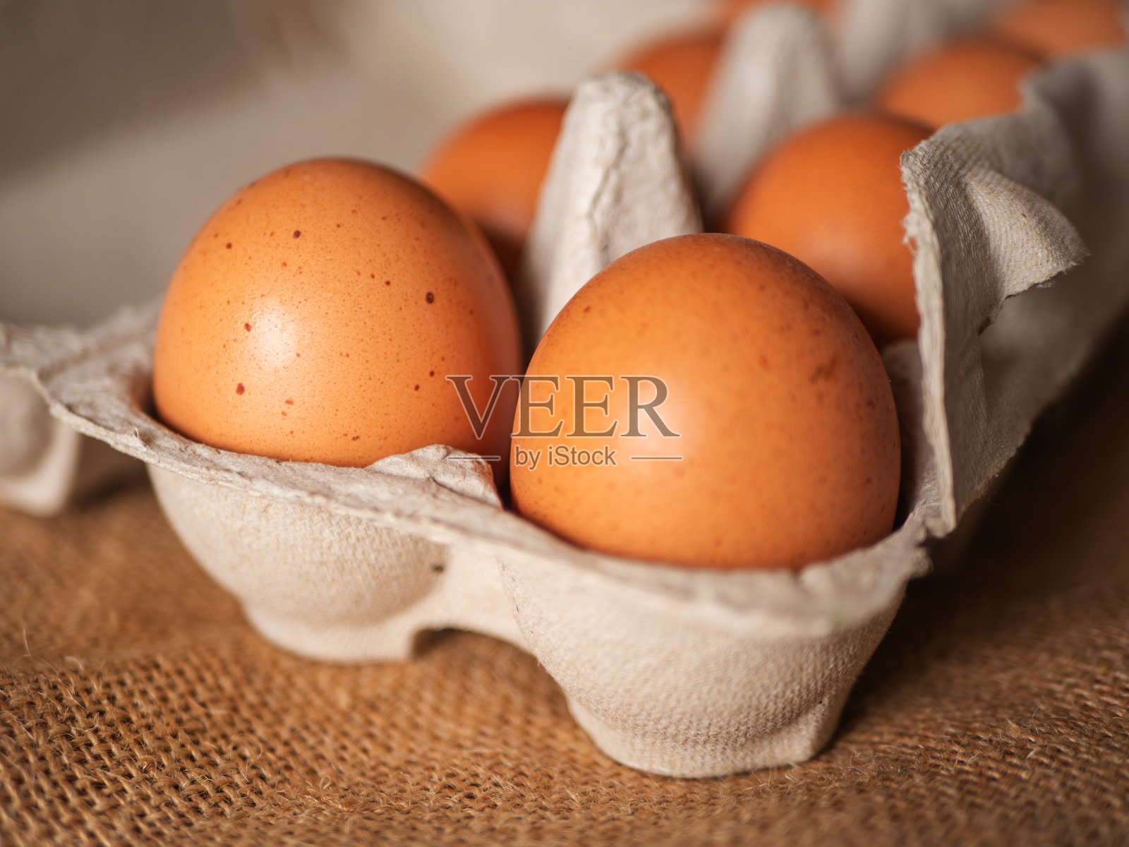 粗麻布背景下纸盒内新鲜鸡蛋的特写照片摄影图片