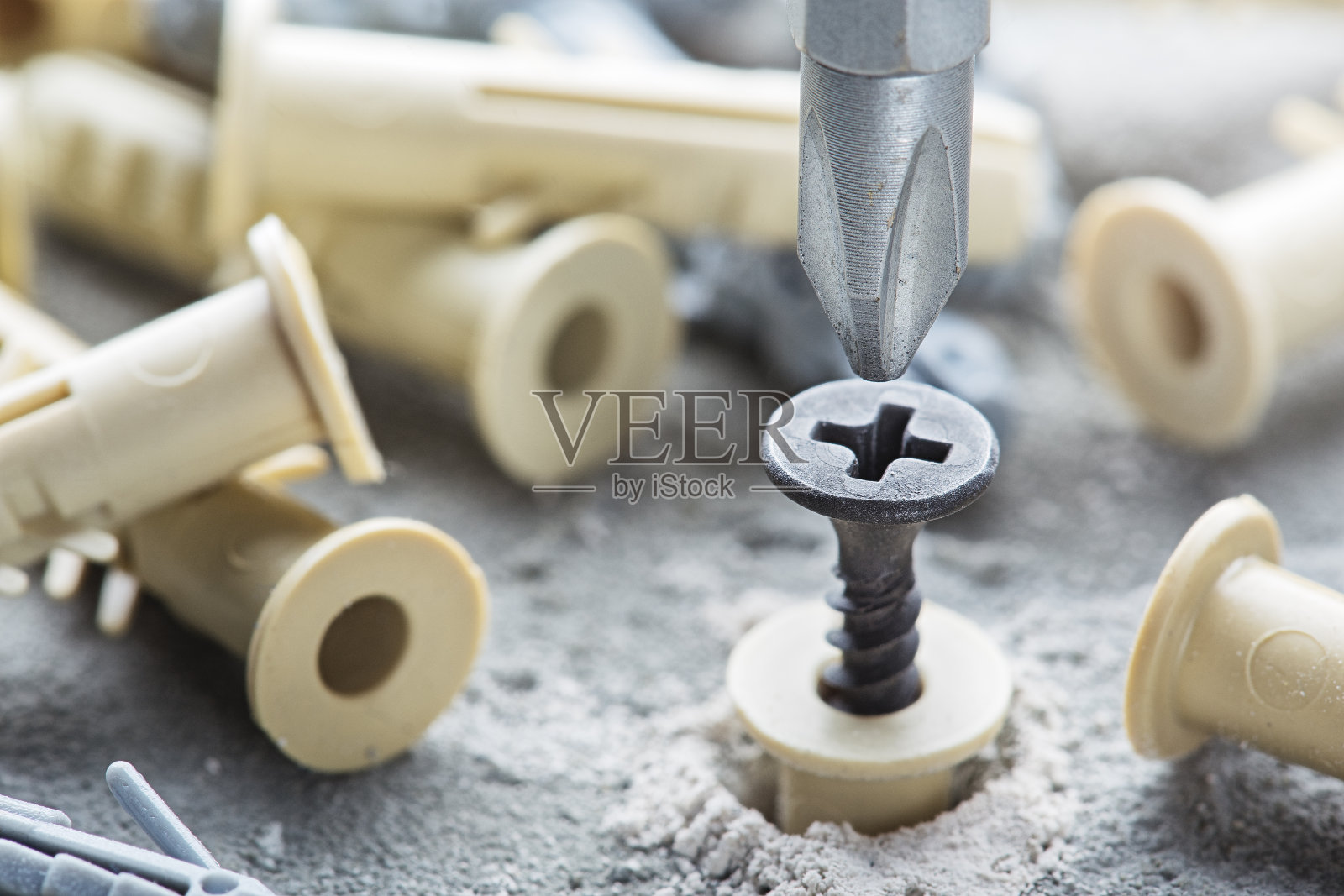 在混凝土墙背景中使用螺丝刀、螺丝和销钉照片摄影图片