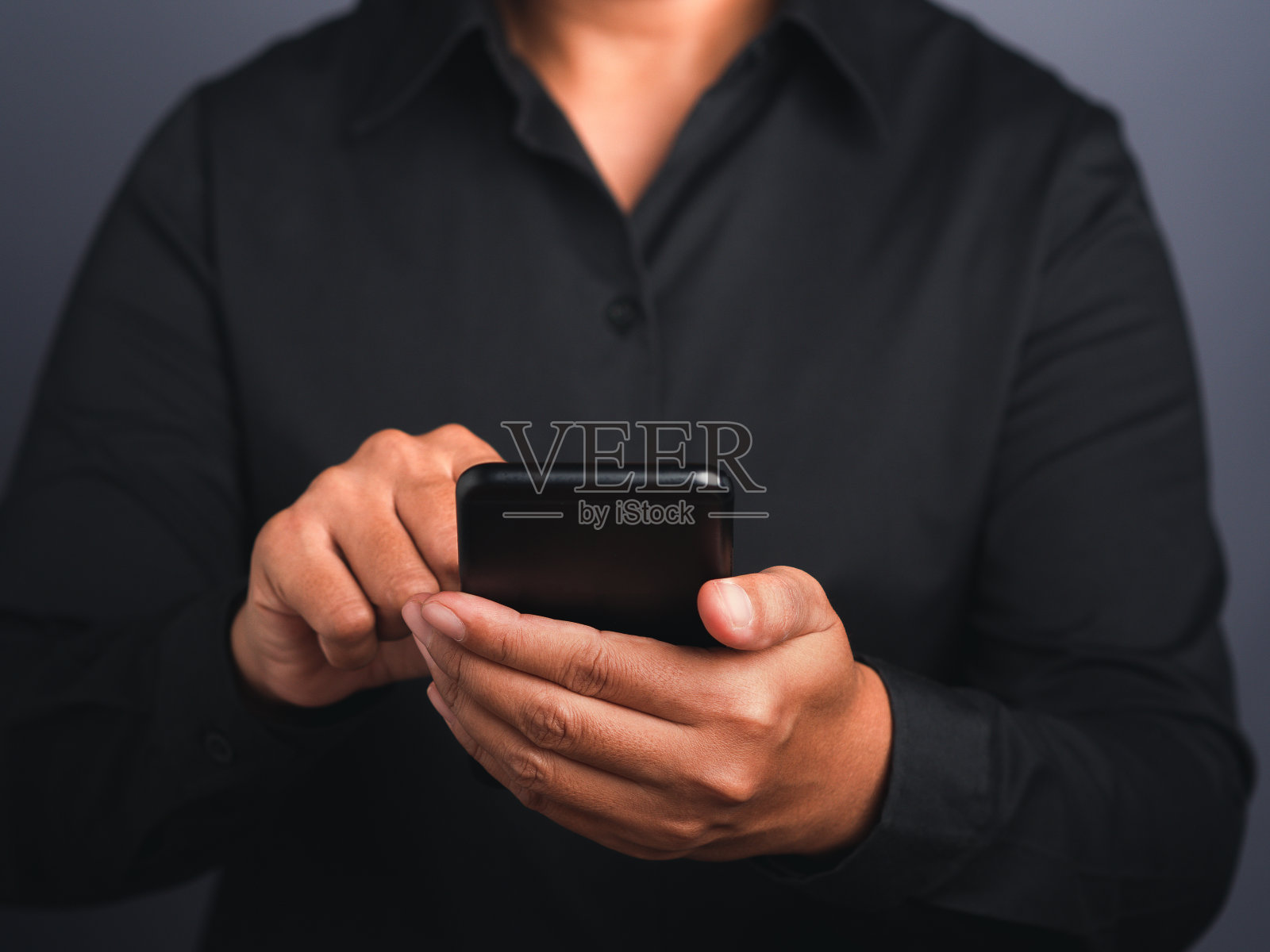 一个女商人手里的智能手机，背景是黑色的。照片摄影图片