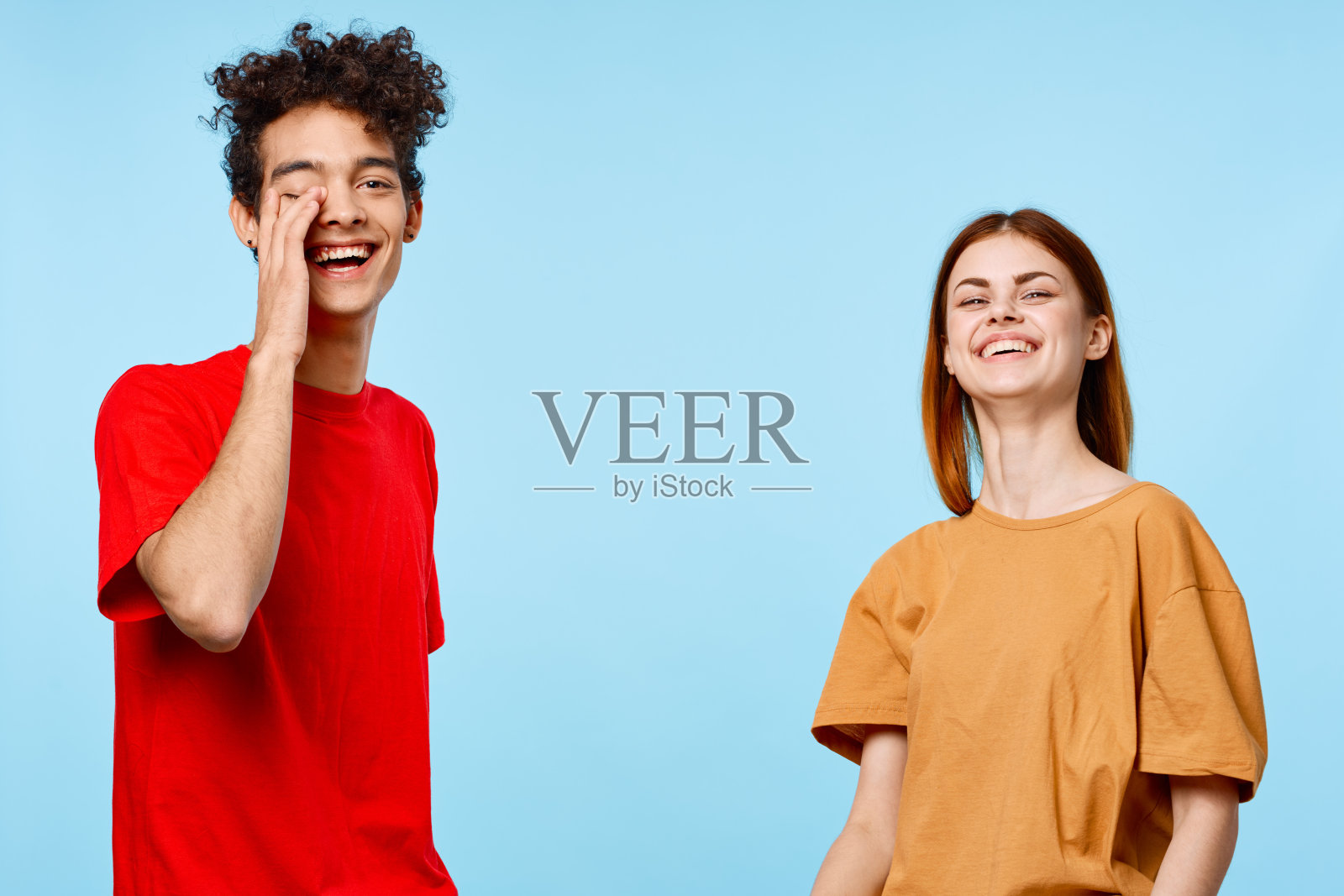 快乐的年轻夫妇穿着五颜六色的t恤交流工作室蓝色背景照片摄影图片