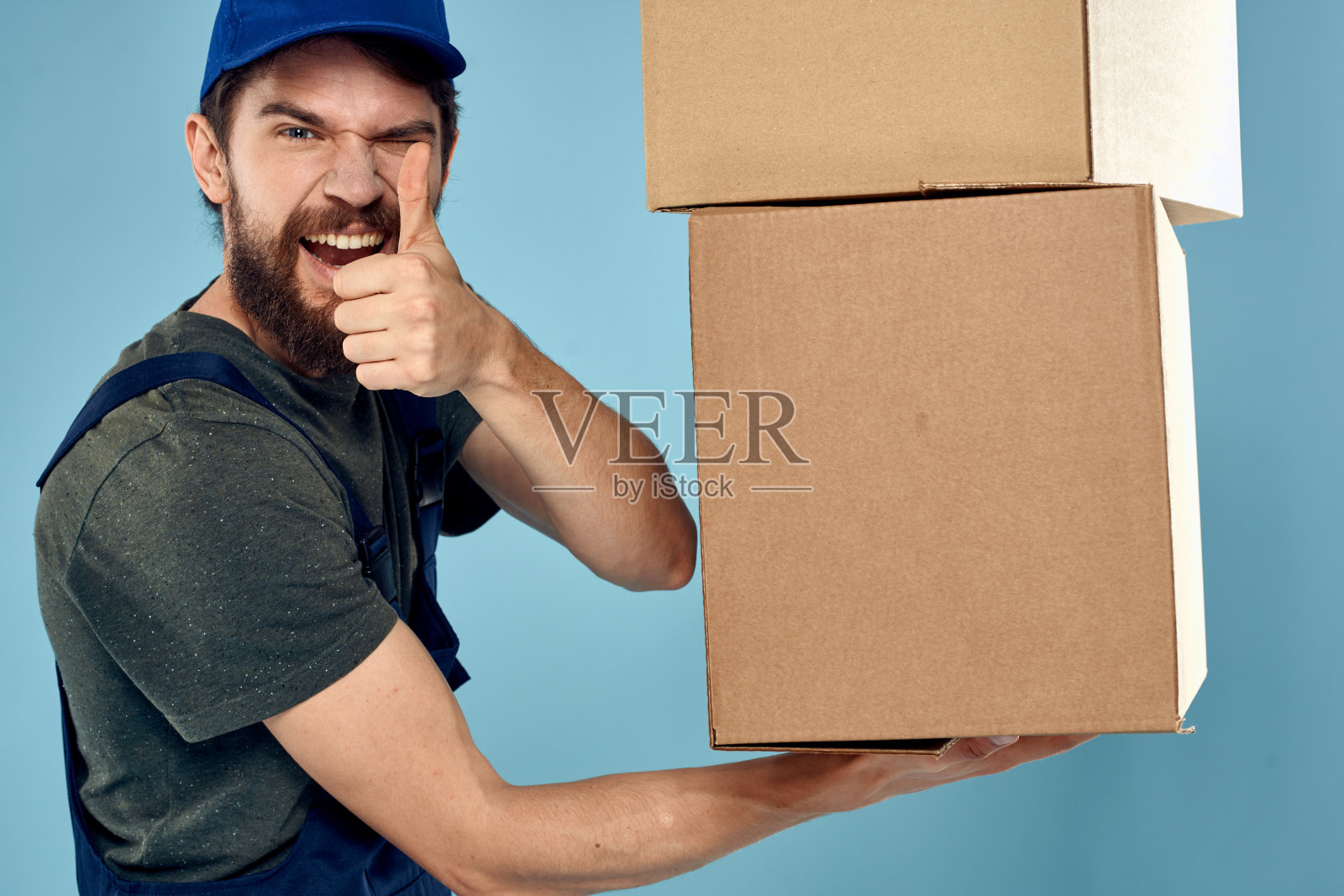 穿着工作服的人，手里拿着箱子，蓝色背景的快递员照片摄影图片