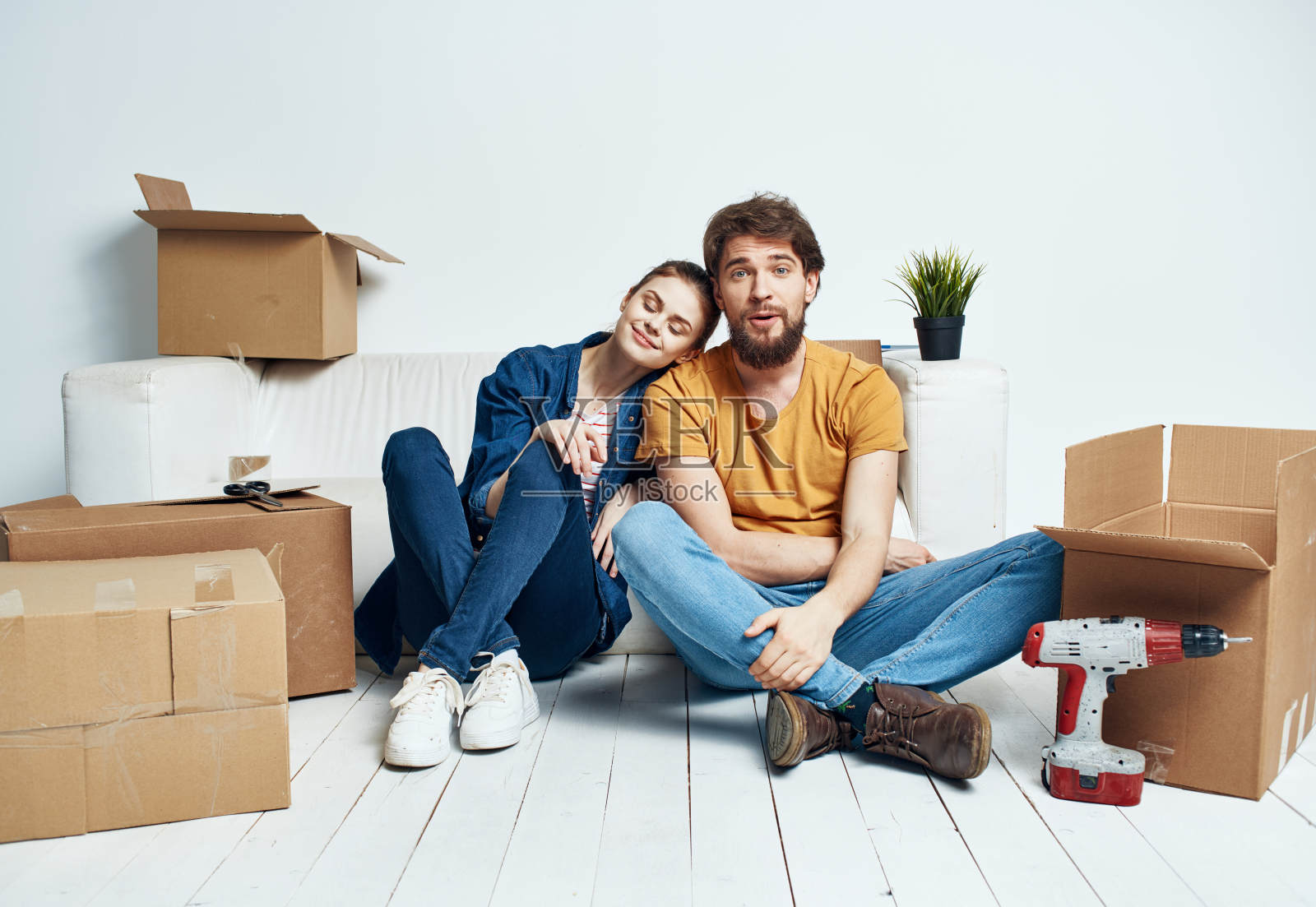 男人和女人坐在地板上，背对着对方，在一个花盆里搬着一朵花照片摄影图片