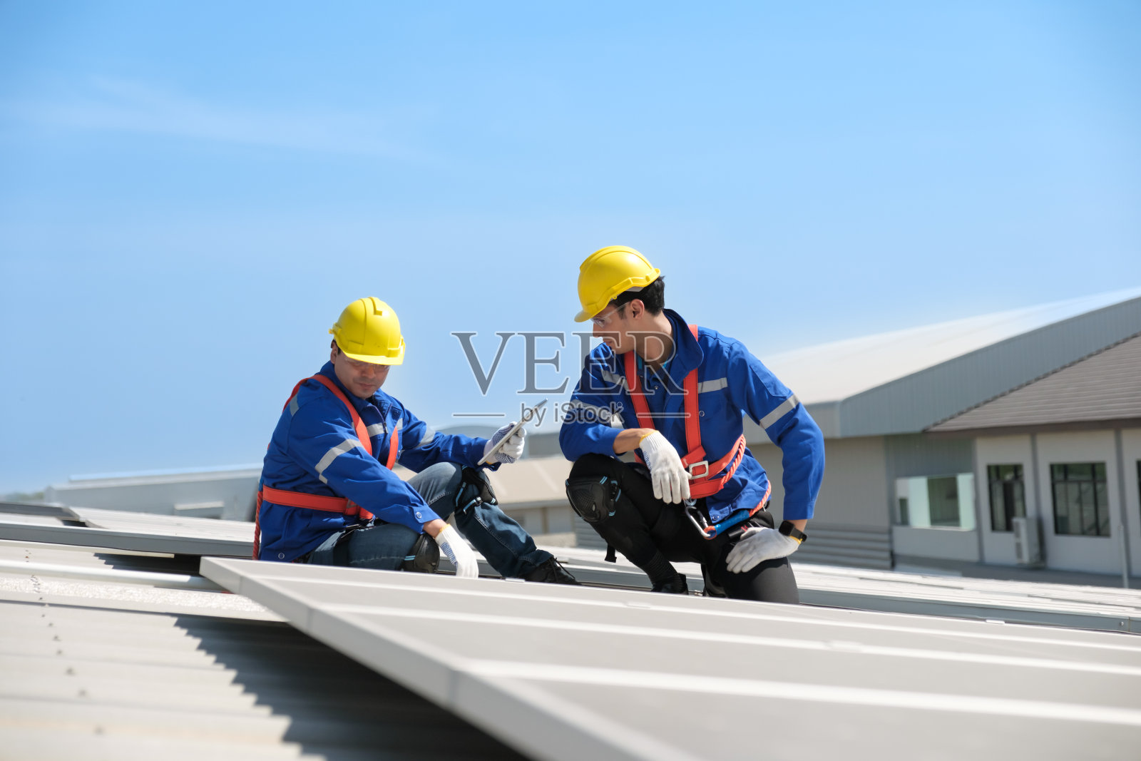 工程师在工厂的屋顶上安装太阳能电池照片摄影图片