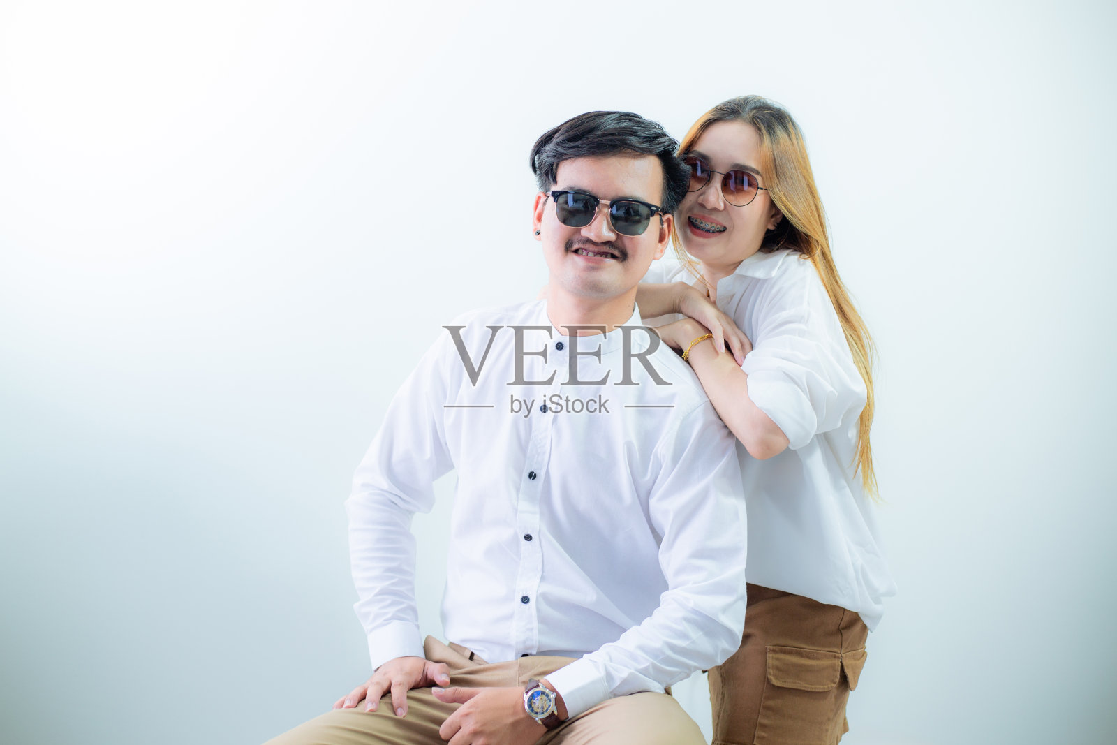 幸福的亚洲夫妇，年轻的亚洲夫妇的肖像坐在白色的盒子，完整的肖像隔离在工作室的白色背景。照片摄影图片