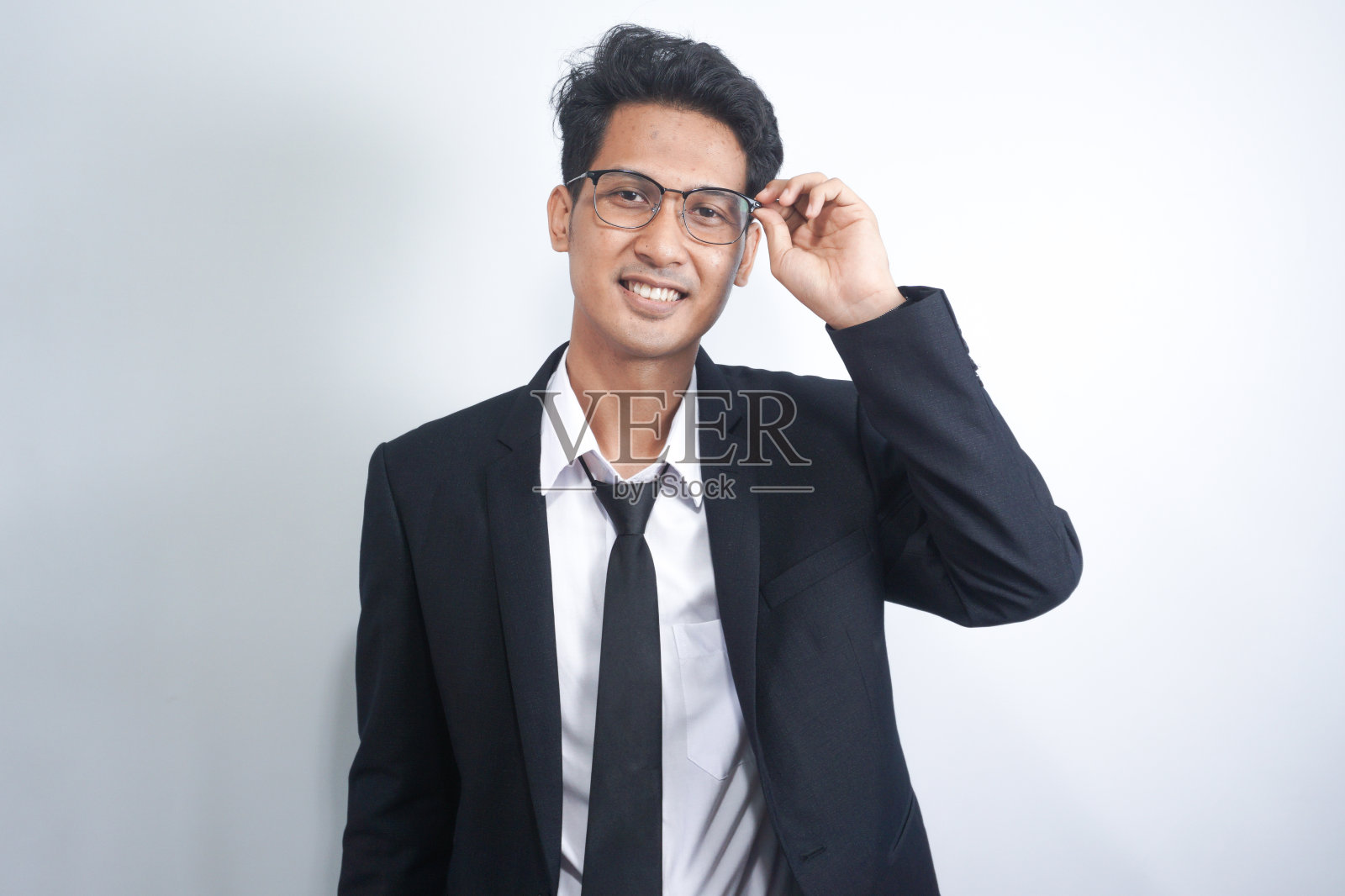 戴眼镜的年轻商人的室内照片，在白色背景上被孤立，直视镜头，表现出自信，为员工提供稳定照片摄影图片