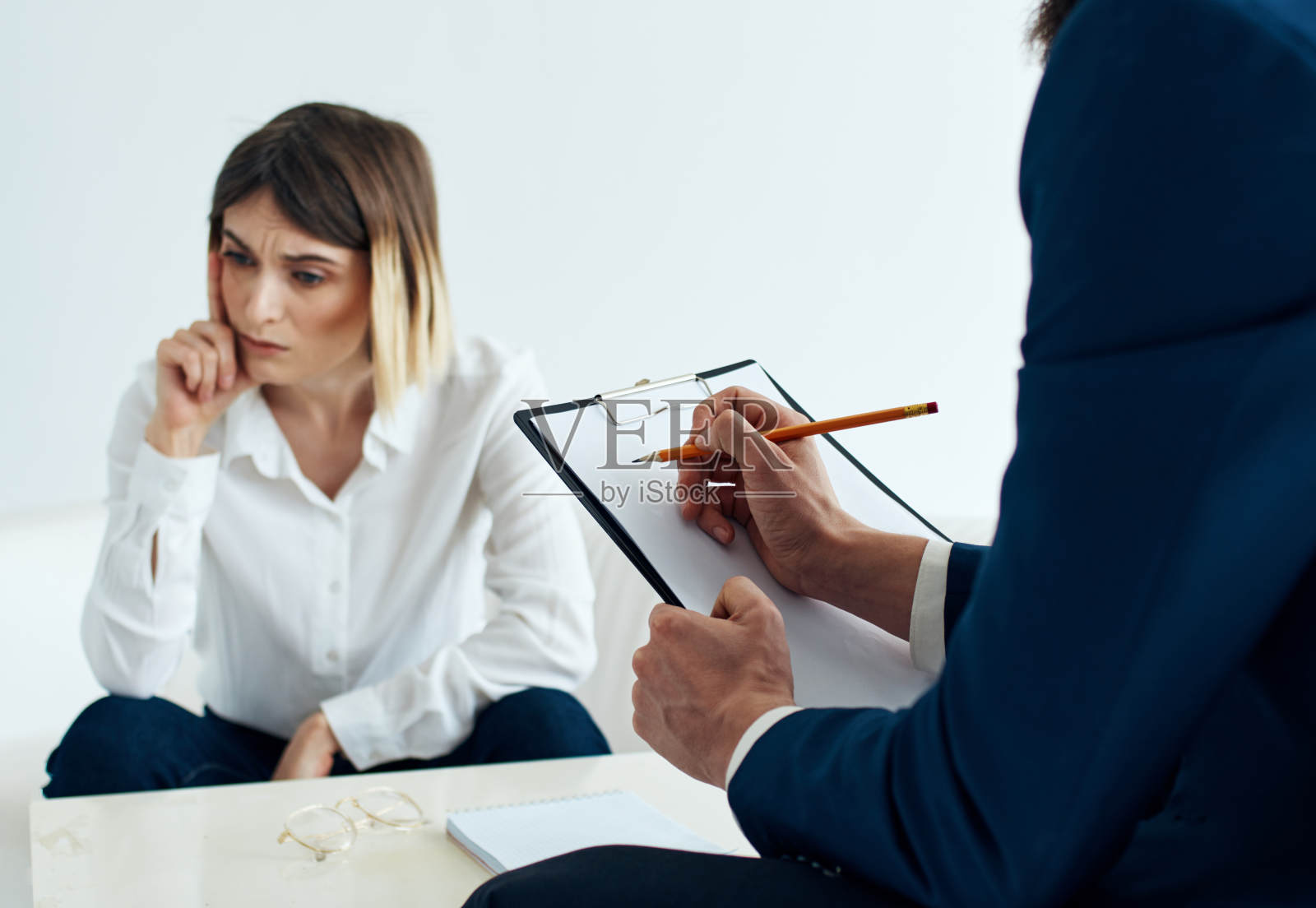 一个穿着经典西装，手里拿着文件的男人和一个情绪化的女人坐在沙发上照片摄影图片