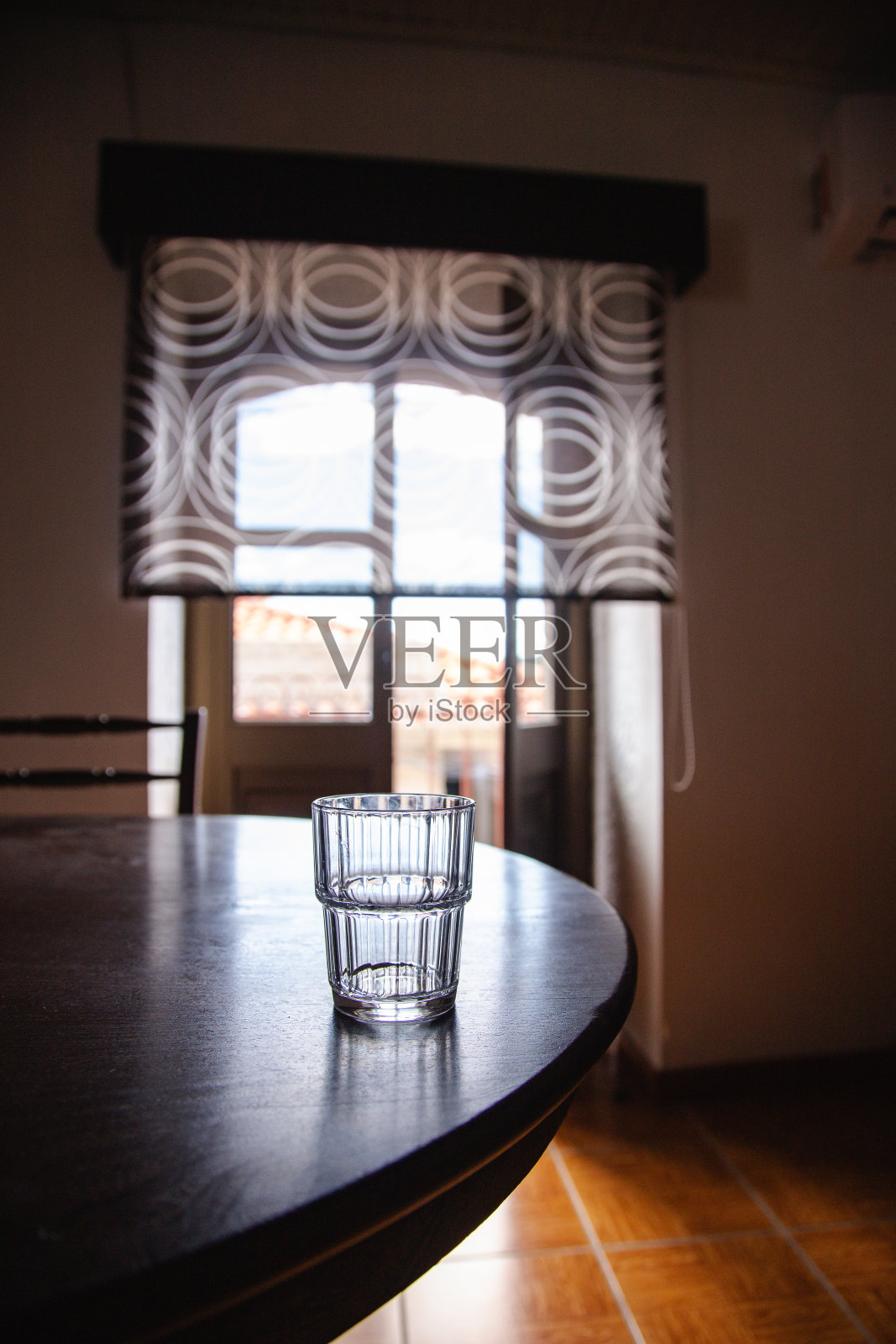 木桌上的空玻璃杯，背景是一扇通向房子外面的敞开的门。沉思的环境。照片摄影图片