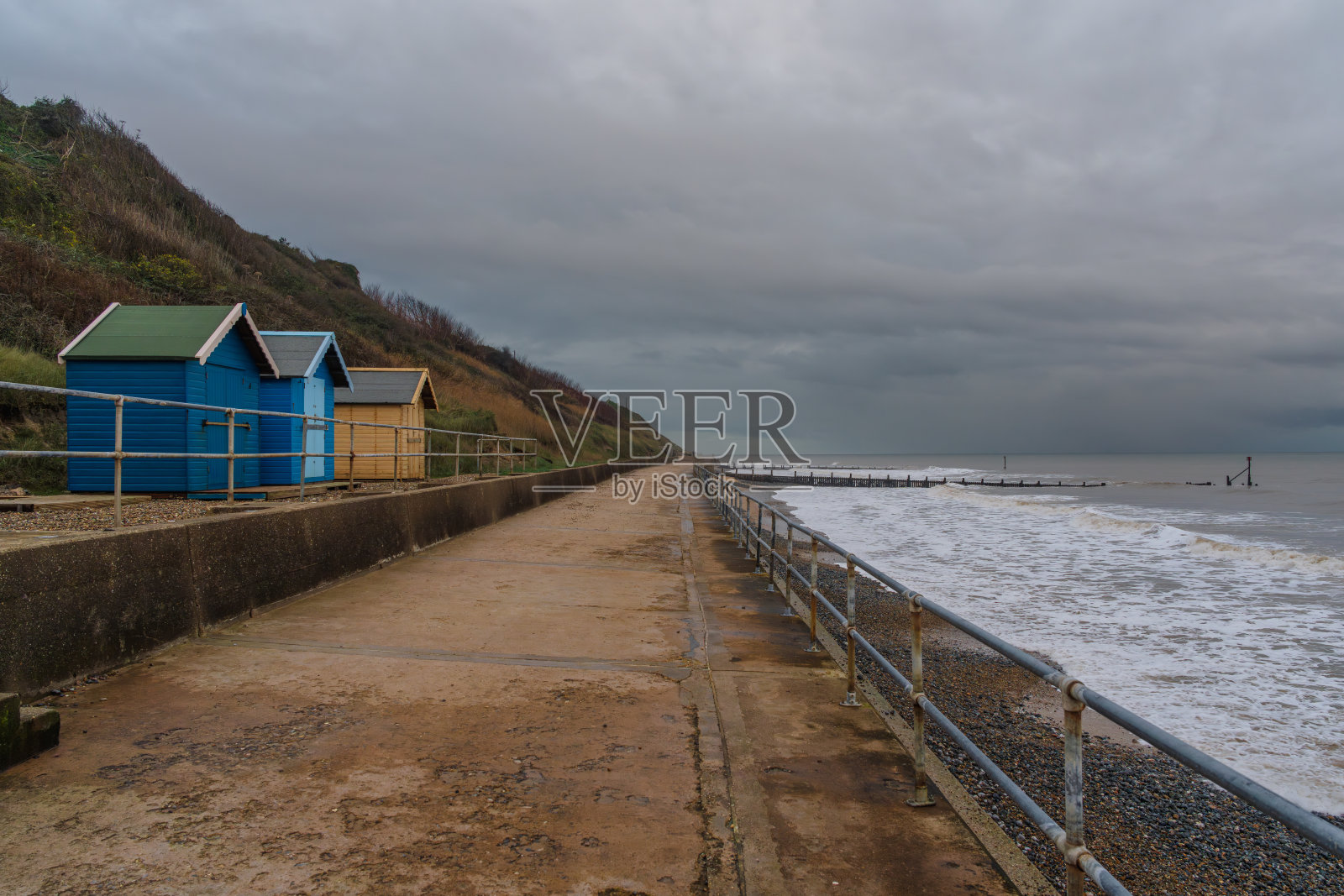 乌云笼罩着英国英格兰诺福克郡Overstrand海滩上的海滩小屋照片摄影图片