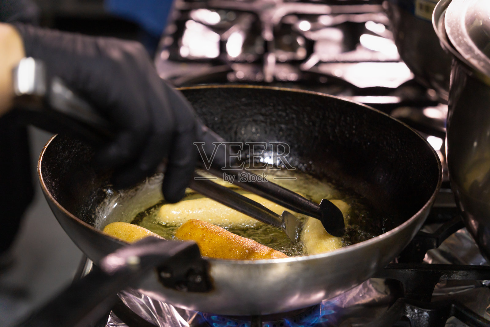 Chvishtari是格鲁吉亚的一种玉米面包，里面有奶酪，在油煎锅里煎。厨师在煎锅里烤荔枝。照片摄影图片