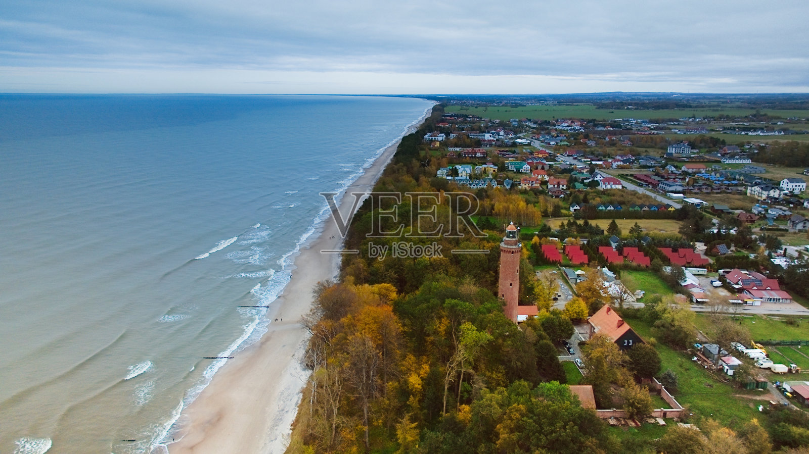 在11月一个多云的日子里，无人机捕捉到Gski灯塔矗立在阴暗的天空中。宁静的大海与温柔的波浪拍打着空旷的海滩，创造了一个宁静的海岸场景，邀请反思和孤独。照片摄影图片