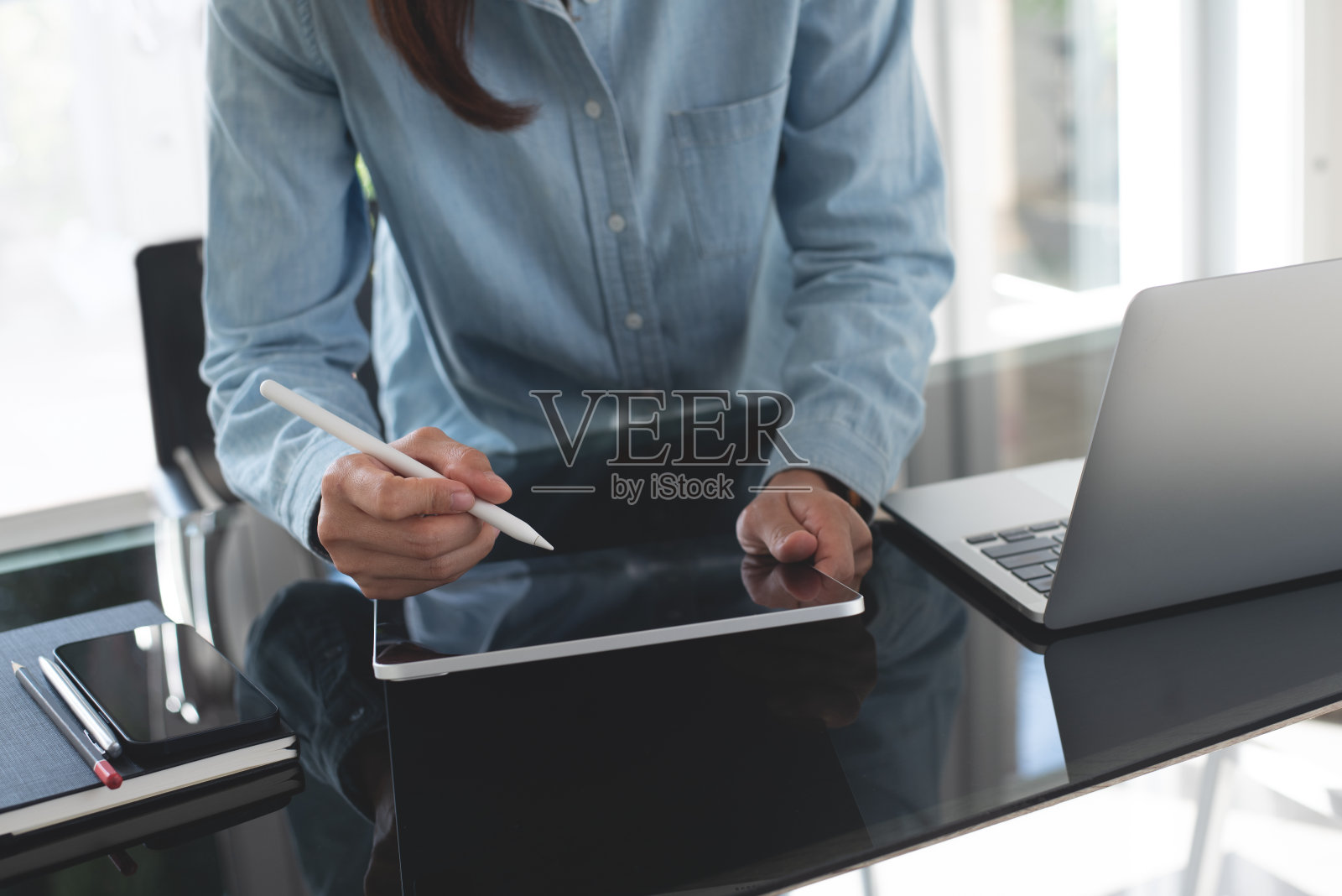 女设计师在工作室办公室工作，使用手写笔、数码平板电脑、笔记本电脑。年轻的休闲女商人，站在办公桌前的自由职业者，在家办公室上网工作照片摄影图片