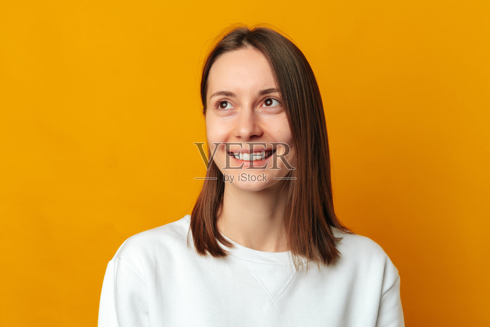 近距离的工作室肖像，一个年轻的微笑的女人在黄色背景。照片摄影图片