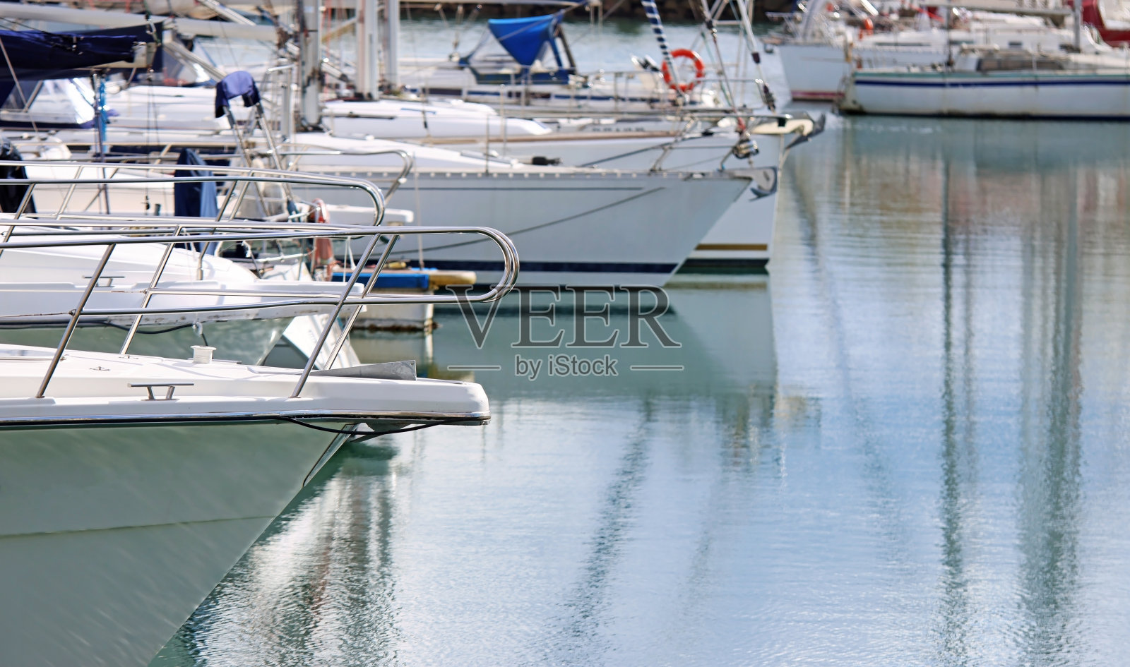 一些游艇的船头停靠在码头上。照片摄影图片