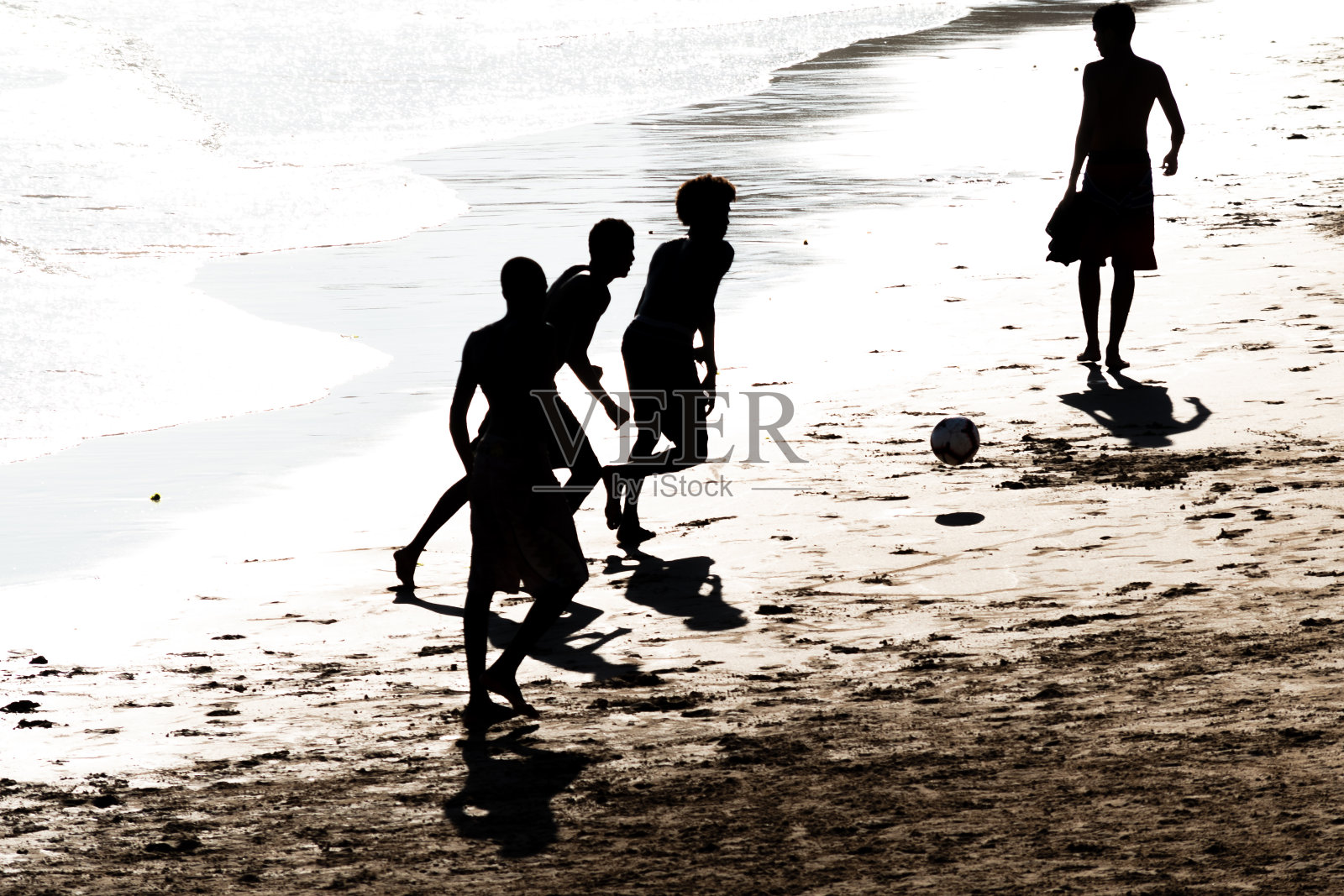 日落时分，人们在巴伊亚州萨尔瓦多的翁迪纳海滩上踢沙滩足球。照片摄影图片