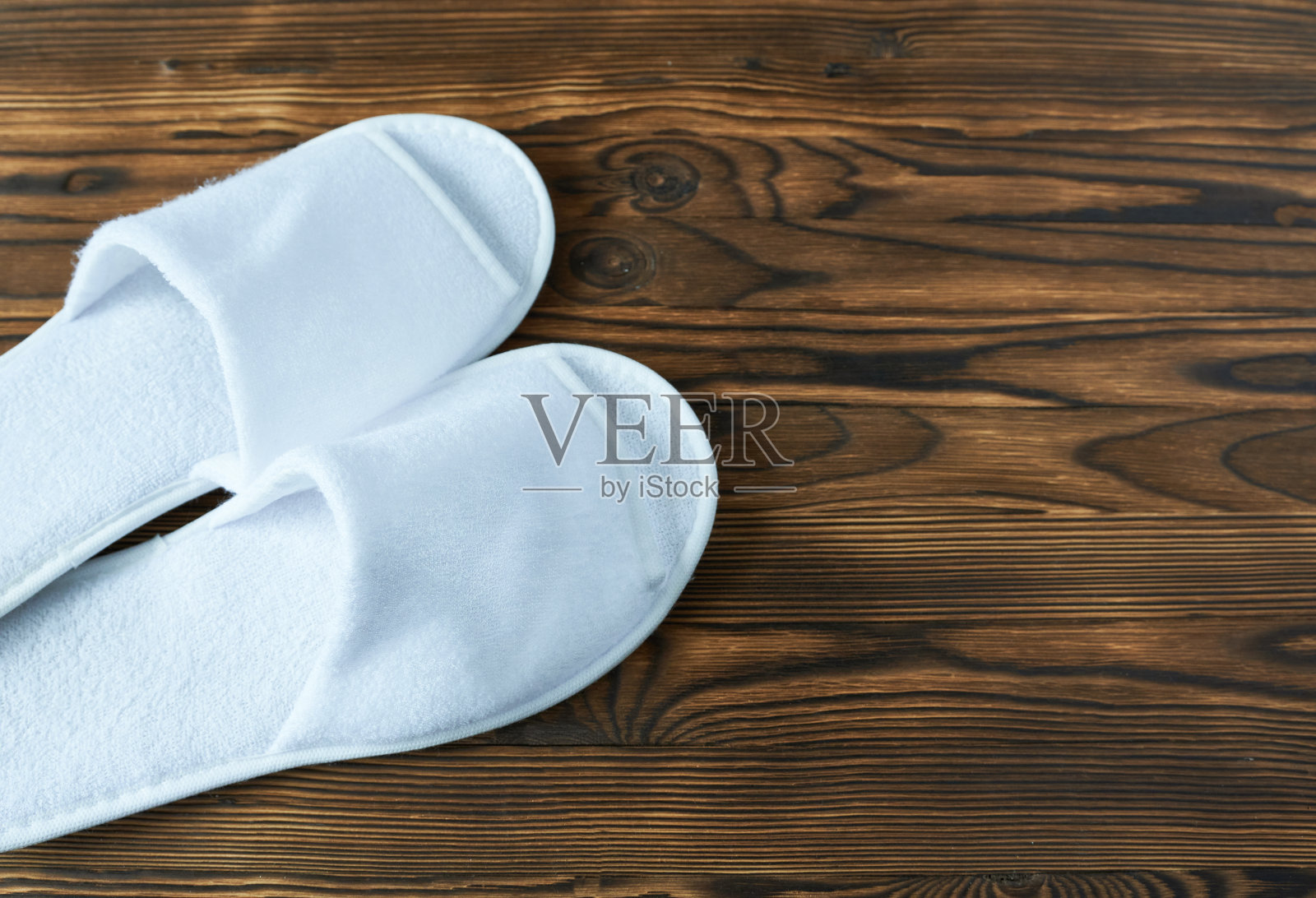 木制背景的白色拖鞋。带复制空间的俯视图。照片摄影图片