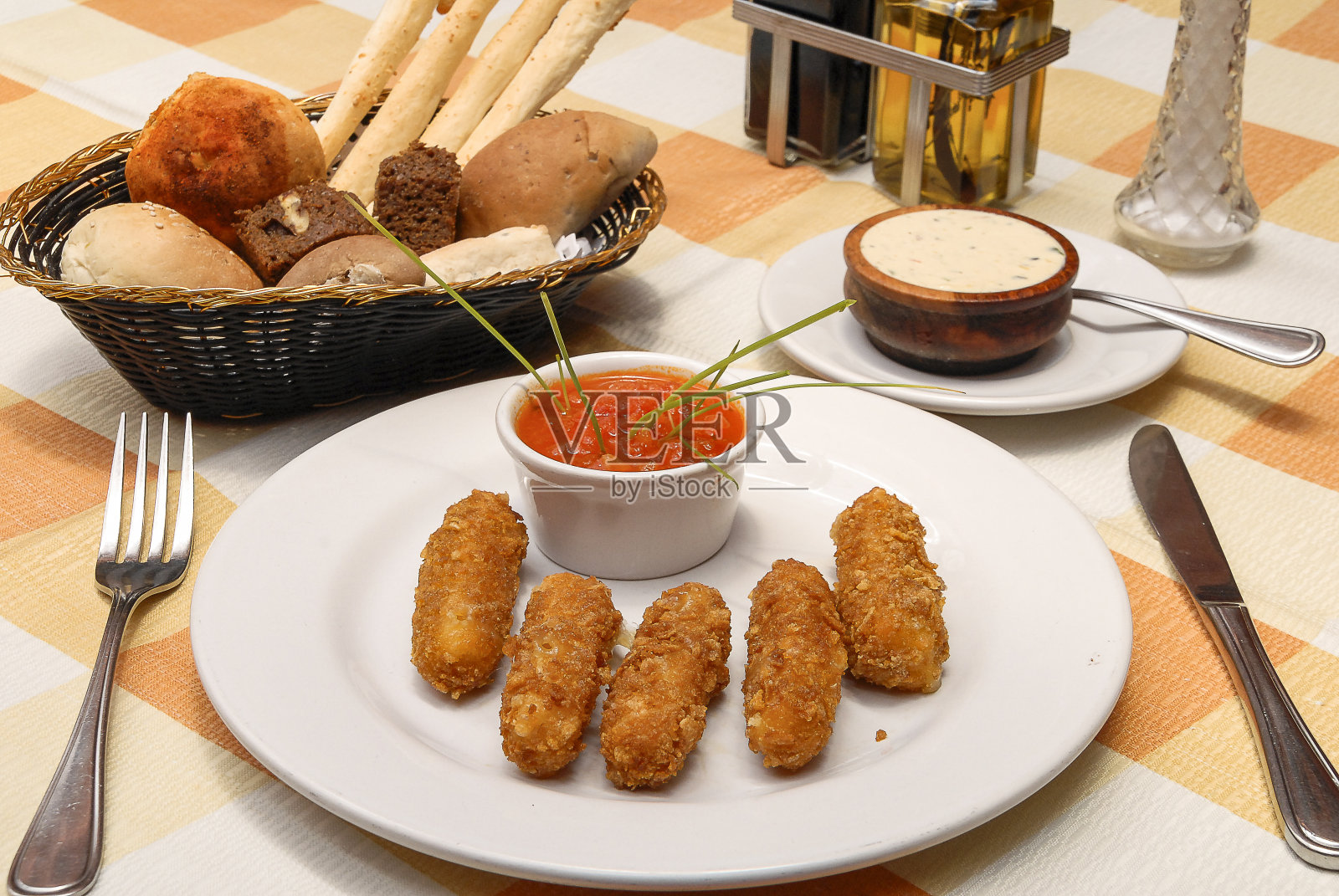 涂了面包屑的曼切戈奶酪手指，还有一篮子面包，橄榄油和黄油放在餐馆的桌子上照片摄影图片