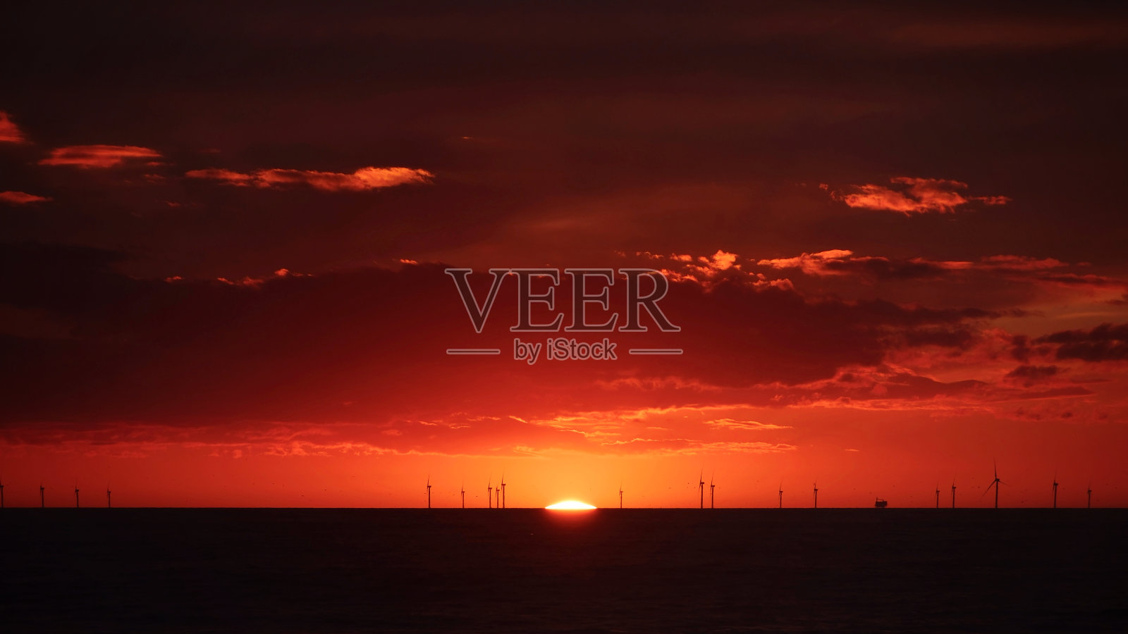 海上日落整齐的风力发电机照片摄影图片