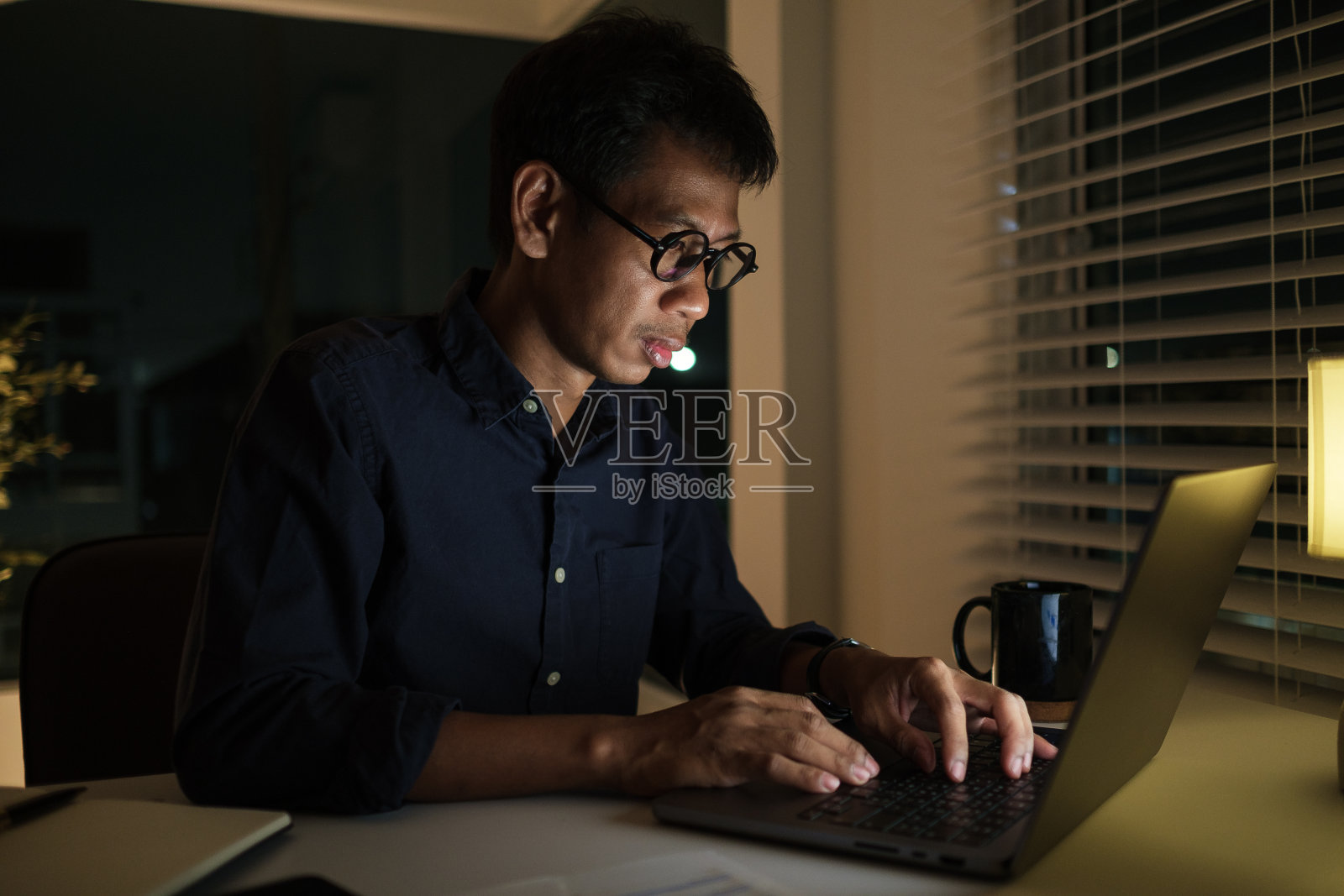 专注的商人晚上在办公室加班。照片摄影图片