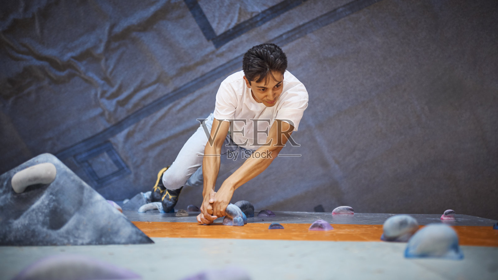 一名男子在室内活动中心攀爬攀岩墙的特写照片摄影图片