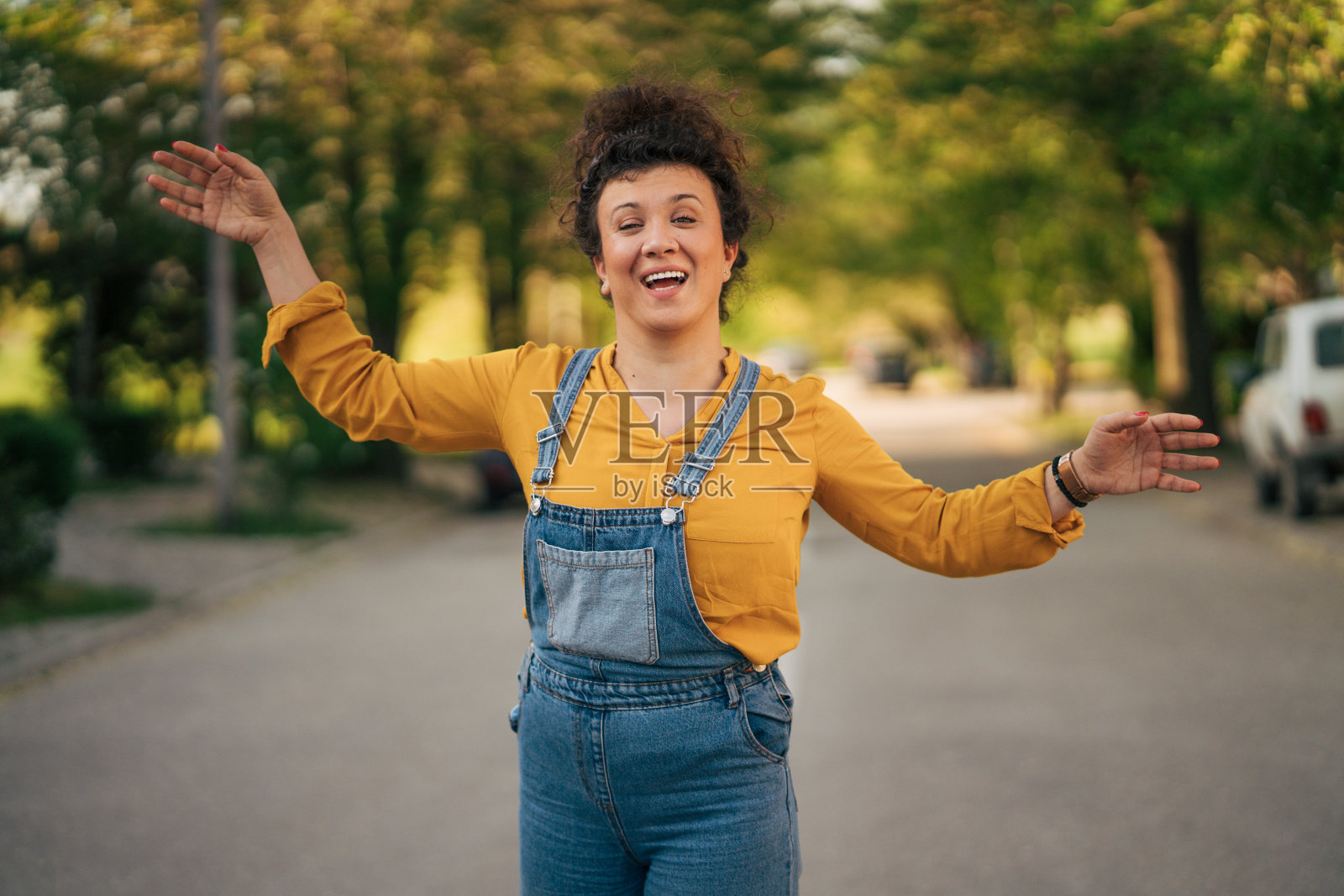 一个快乐的女人站在街上，张开双臂。照片摄影图片