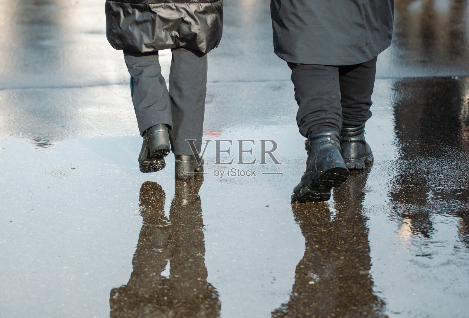 在一个寒冷的冬日，一个男人和一个女人正走过一个水坑照片摄影图片