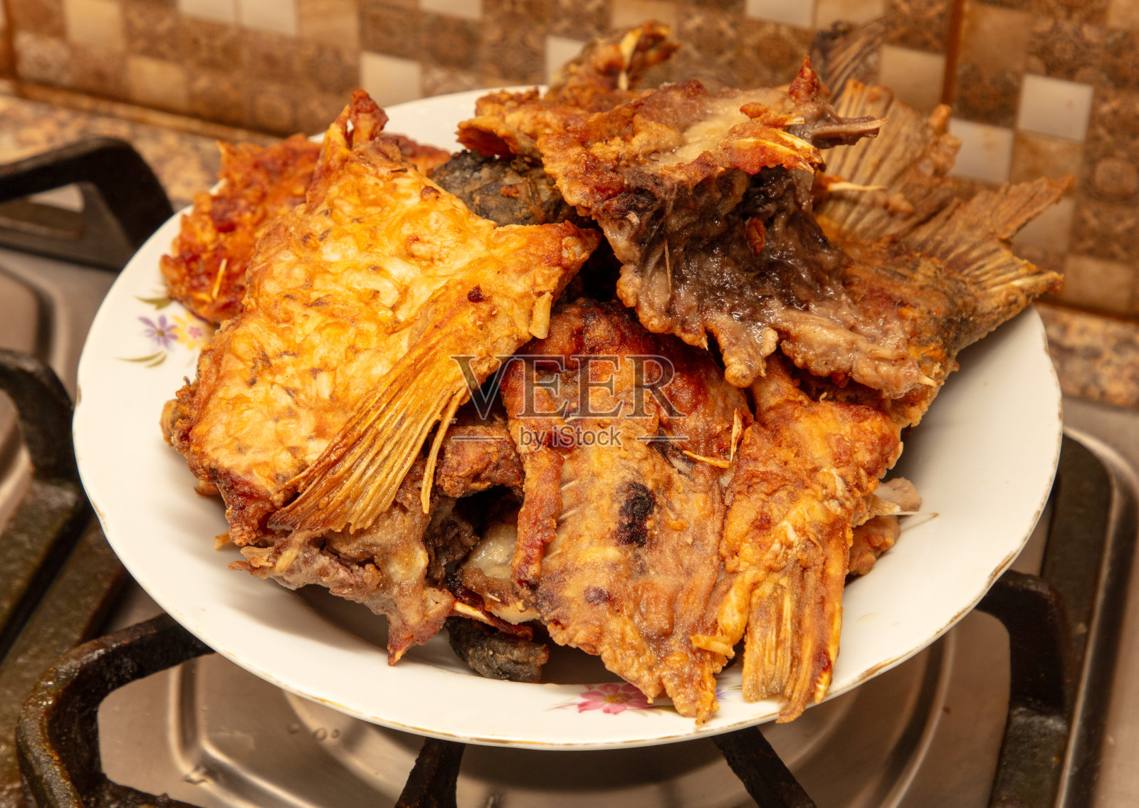 厨房煤气炉上的白盘子里的煎鱼照片摄影图片