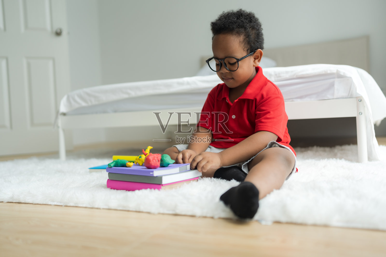 可爱的小男孩在地上用橡皮泥做东西，微笑着跟随你的想象。照片摄影图片