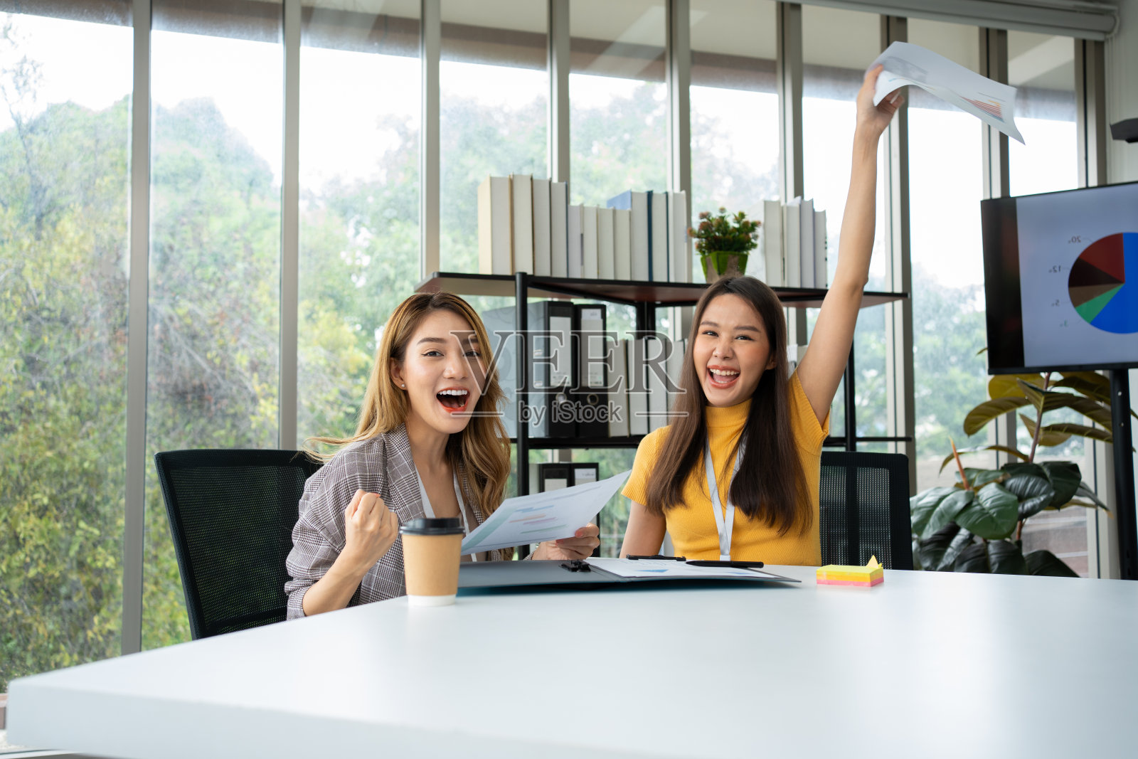 亚洲聪明的办公室或女商人兴奋成功的商人，庆祝胜利。两个女商人在看月度销售总结，他们超额完成了销售目标，实现了利润增长照片摄影图片