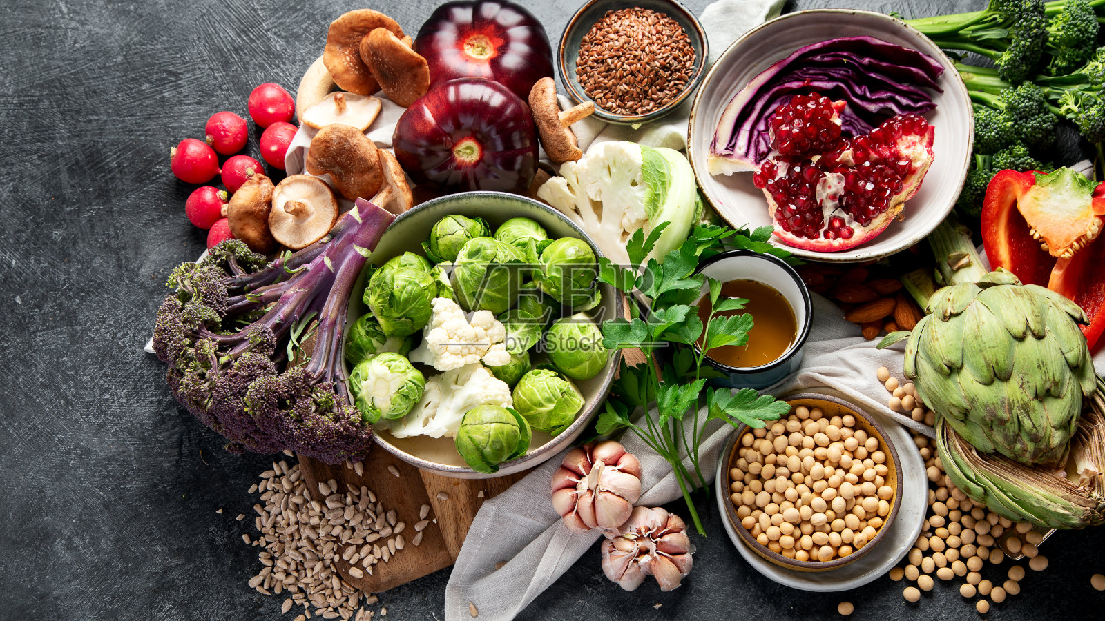 素食食物。胡椒，花椰菜，卷心菜，大蒜，蘑菇，石榴，黑色背景照片摄影图片