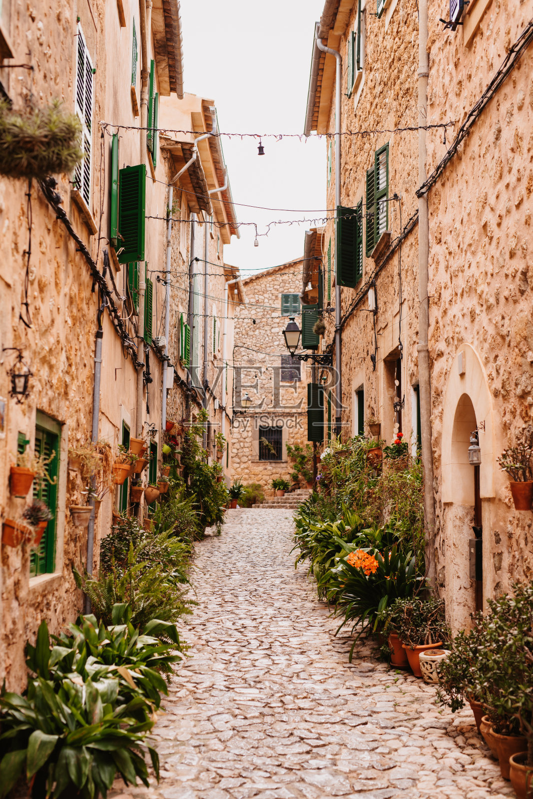 在迷人的瓦尔德莫萨村，风景如画的小巷装饰着五颜六色的花盆，映衬着质朴的砂岩墙照片摄影图片