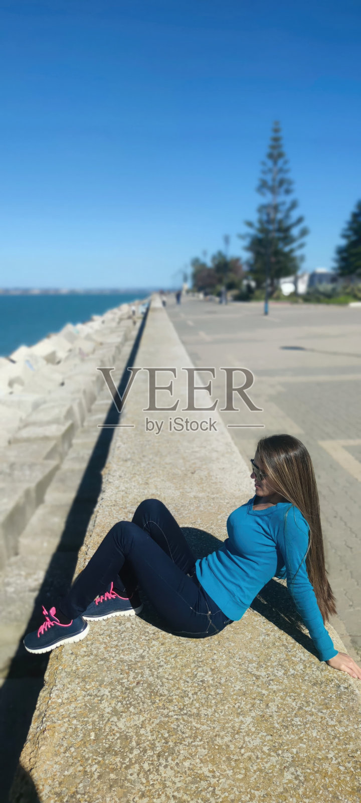 年轻女子放松地摆姿势，看着大西洋。加的斯，安达卢西亚，西班牙照片摄影图片