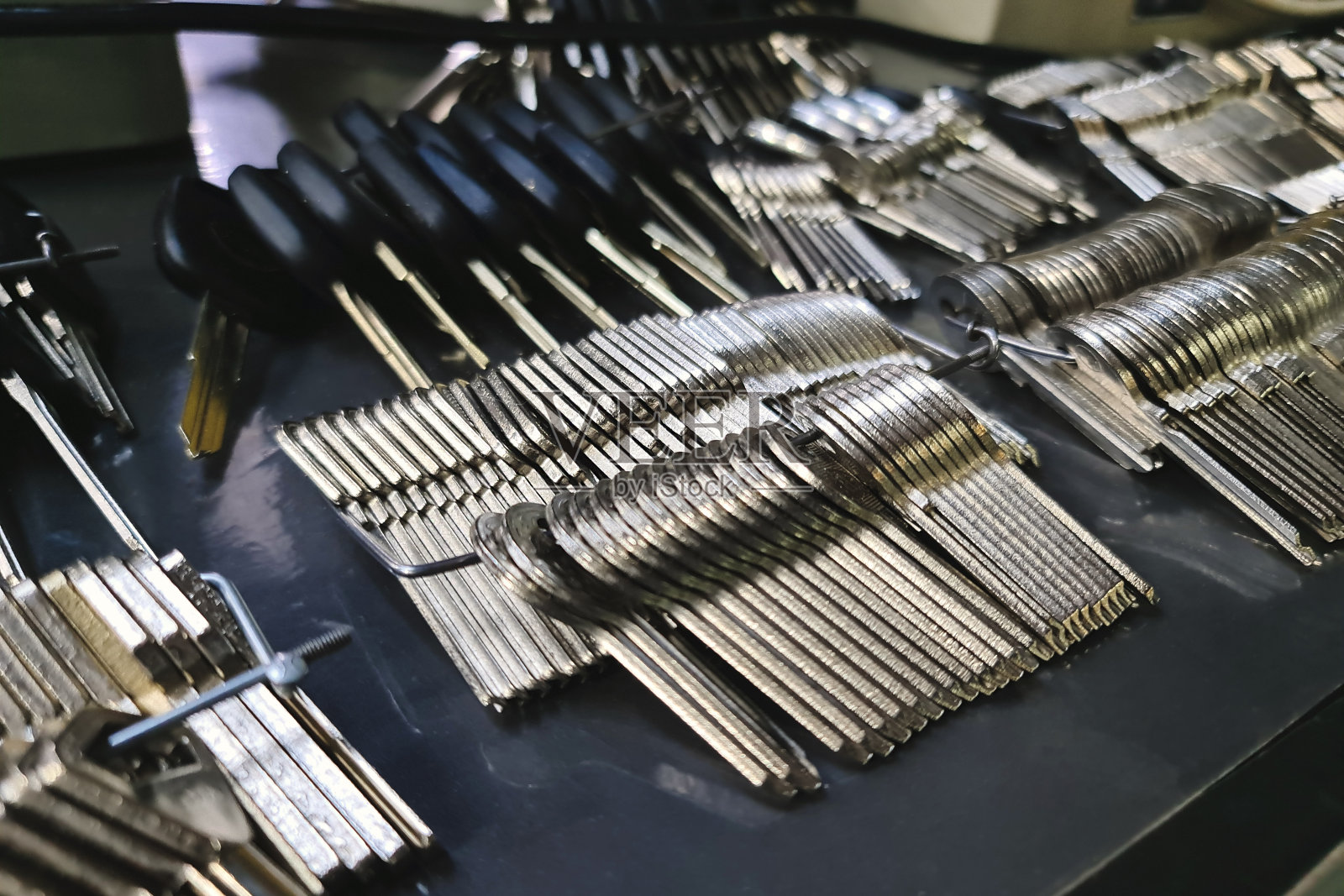 一个师傅的桌子上有很多用来复制钥匙的空白，他按订单复制钥匙照片摄影图片