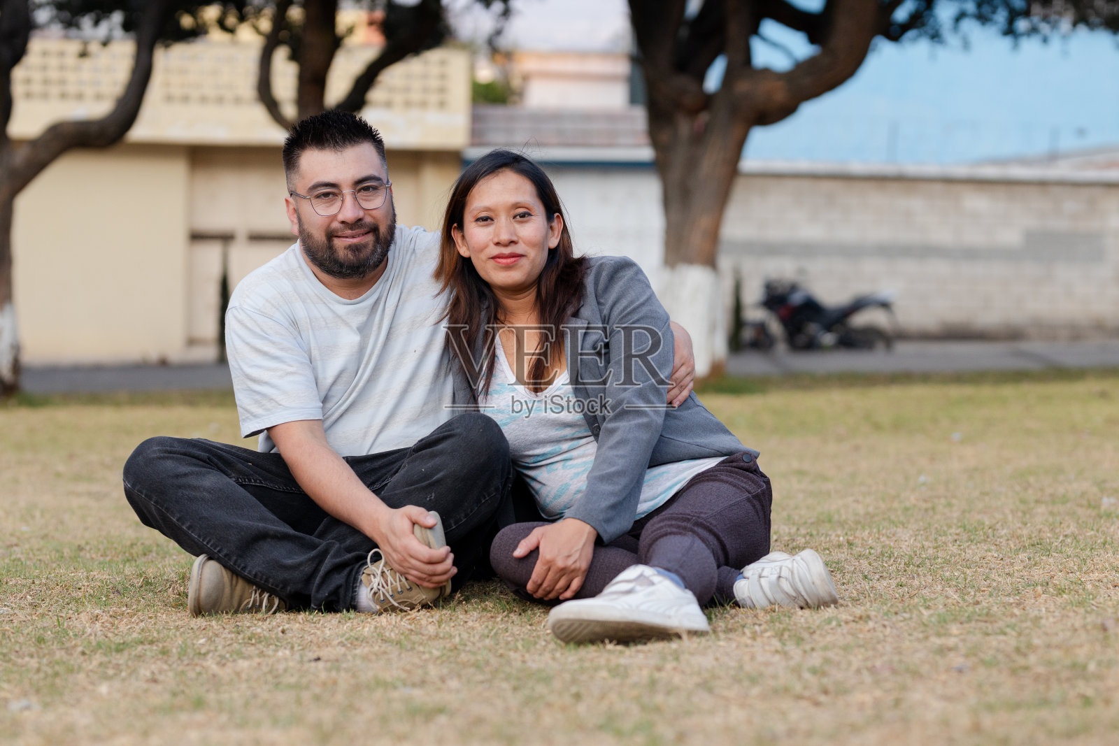坐在田野里的西班牙夫妇-在公园里相爱的年轻夫妇-年轻的父母-新婚夫妇-拉丁美洲的成年夫妇照片摄影图片