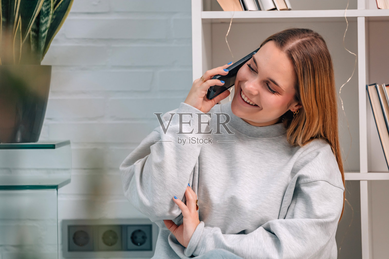 金发女孩坐在家里的地板上讲手机照片摄影图片