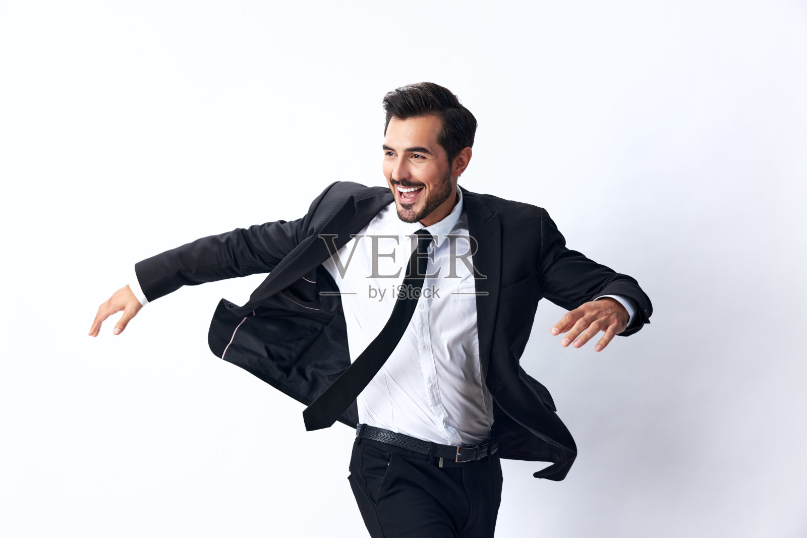 一个商人穿着西装跳了起来，在白色孤立的背景上露出牙齿微笑。快乐商人的概念照片摄影图片