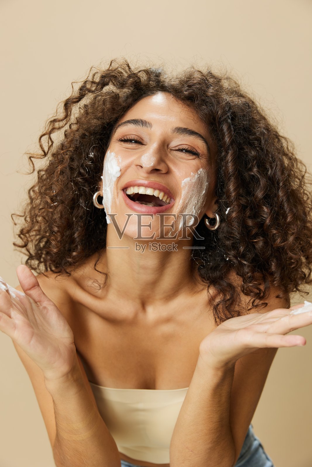 女性美容脸部特写:用手的手指涂抹泡沫清洗和清洁皮肤，指甲和头发健康，吹风机风格卷曲的非洲发型，身体和美容护理概念照片摄影图片